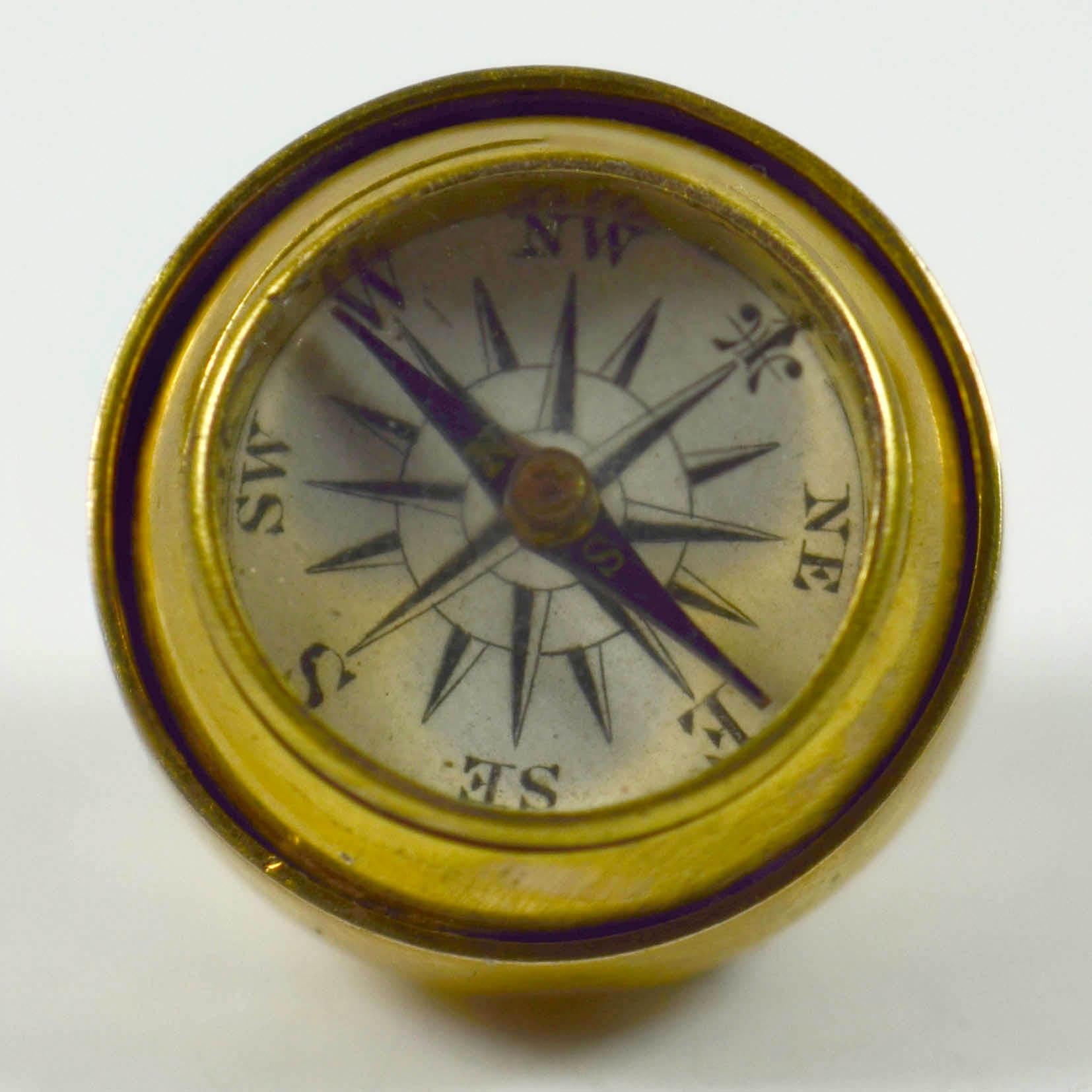An antique fob or charm designed as a ball with rotating section, opening to display a compass. The fob is unmarked, but tests as high karat gold. The compass is in good working order, and has a blue magnetic needle with N and S marked in gold. The