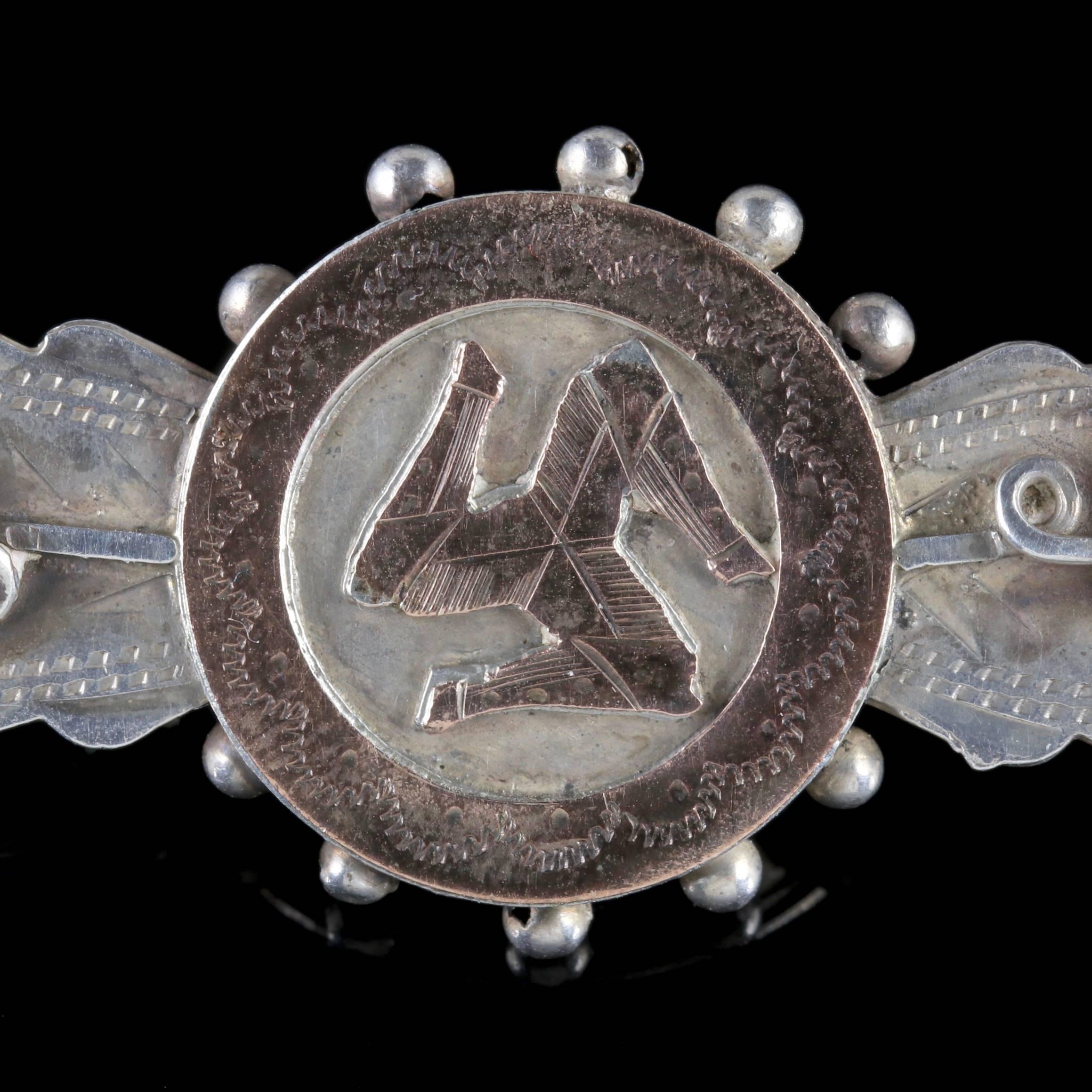 This beautiful antique Sterling Silver brooch is Victorian dated Birmingham 1900. 

The brooch displays beautiful engraved workmanship with flowers at either side and a golden Triskelion in the centre.

The Triskelion is an ancient symbol made up of