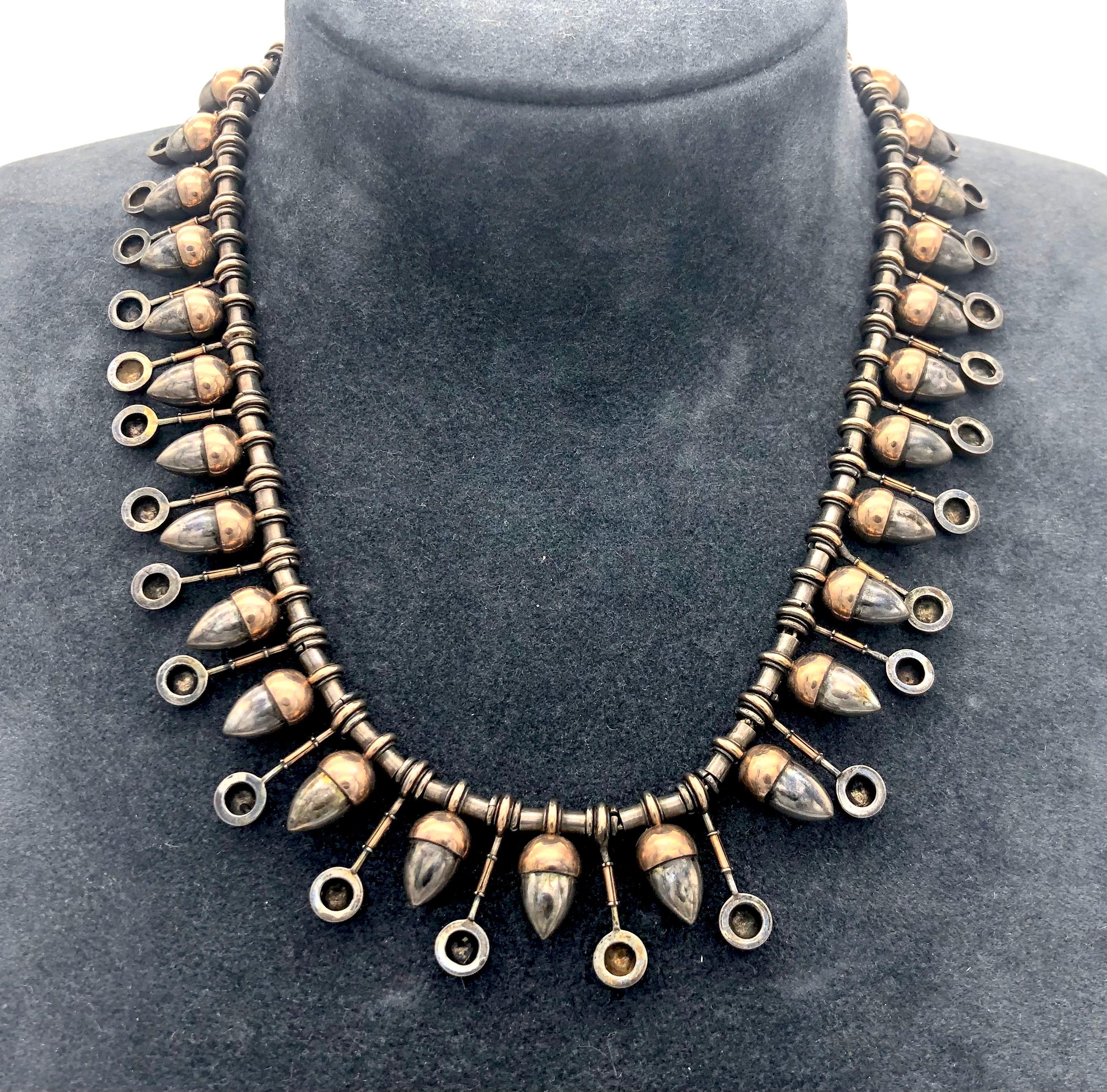 This Geek Revival necklace was made out of silver in the 1870s. Thirty acorns, partially gilt with red gold, alternate with twenty eight longer elements that terminate in half balls, also partially gilt.  All elements are articulated and threaded