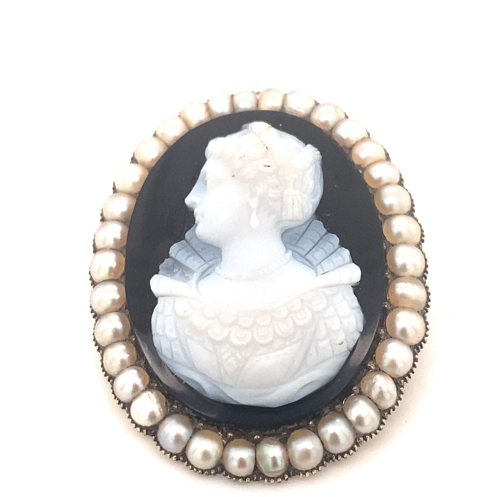 This is a stunning detailed hardstone cameo brooch set with a halo of pearls in 14k Gold.  The cameo depicts a detailed woman with Victorian clothes and jewelry. The brooch is set with 33 pearls that have nice luster.  The brooch measures 36mm wide