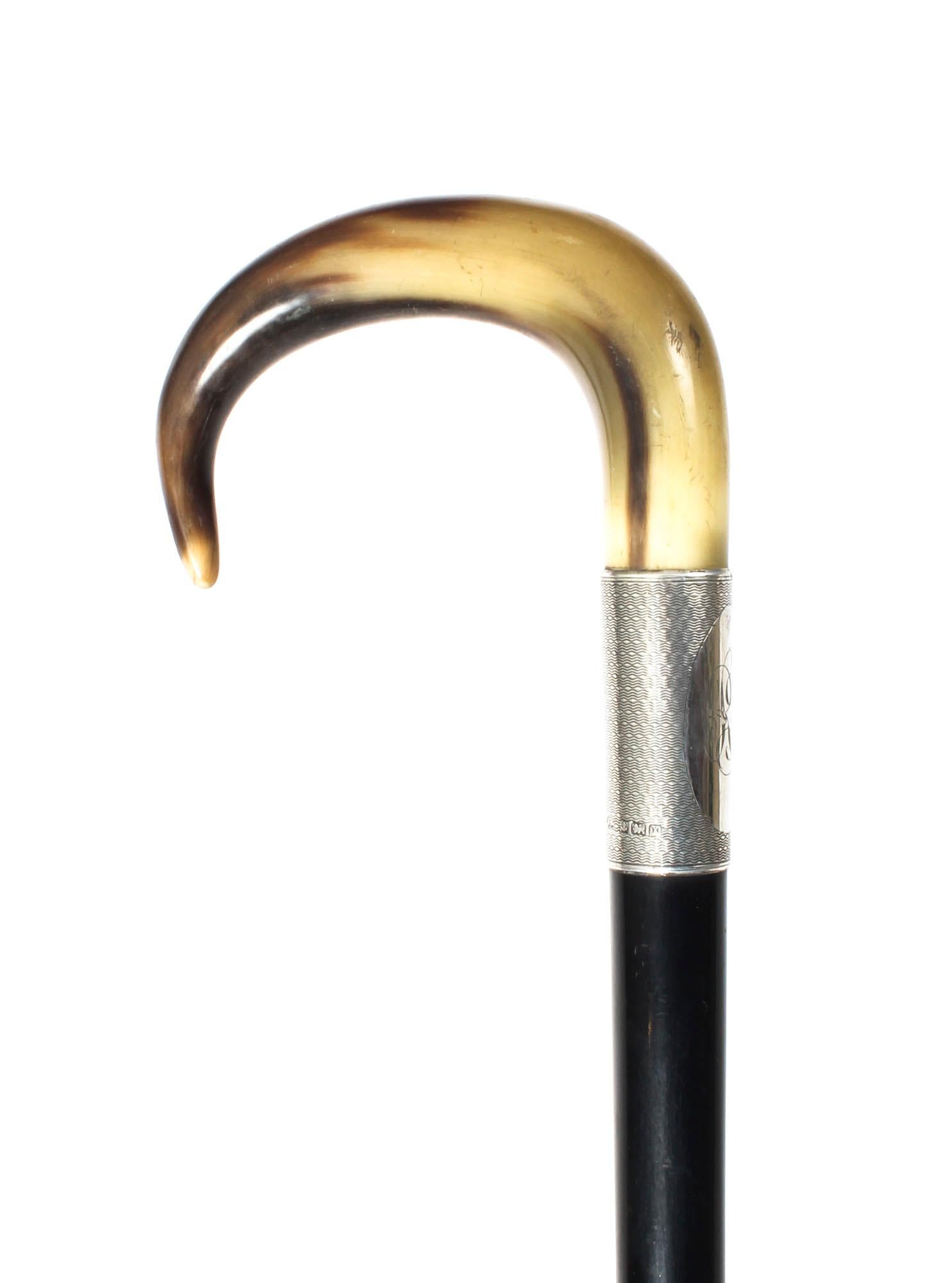 This is a beautiful antique George V horn handled ebonized walking stick, the silver collar bears hallmarks for Birmingham, 1922.

The horn handle is exquisitely carved in 'C' shape and features a broad monogrammed engine turned silver ferrule