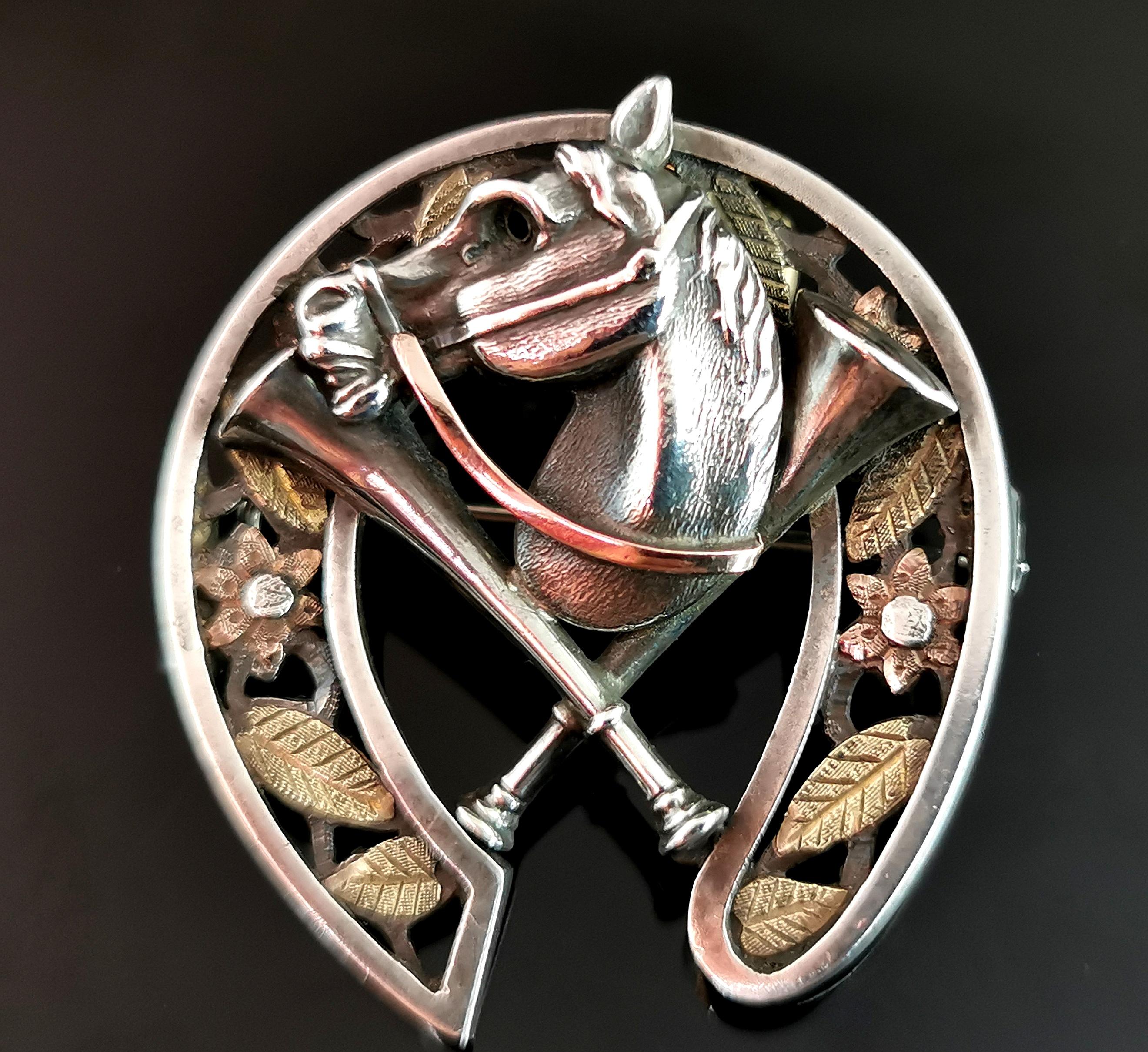 A scarce and unusual antique Victorian era brooch.

It is modelled as a horseshoe in sterling silver with bi colour, yellow and rose gold foliate overlay around the shoe.

The centre has a sterling silver horses head wearing a bridle with Rose gold