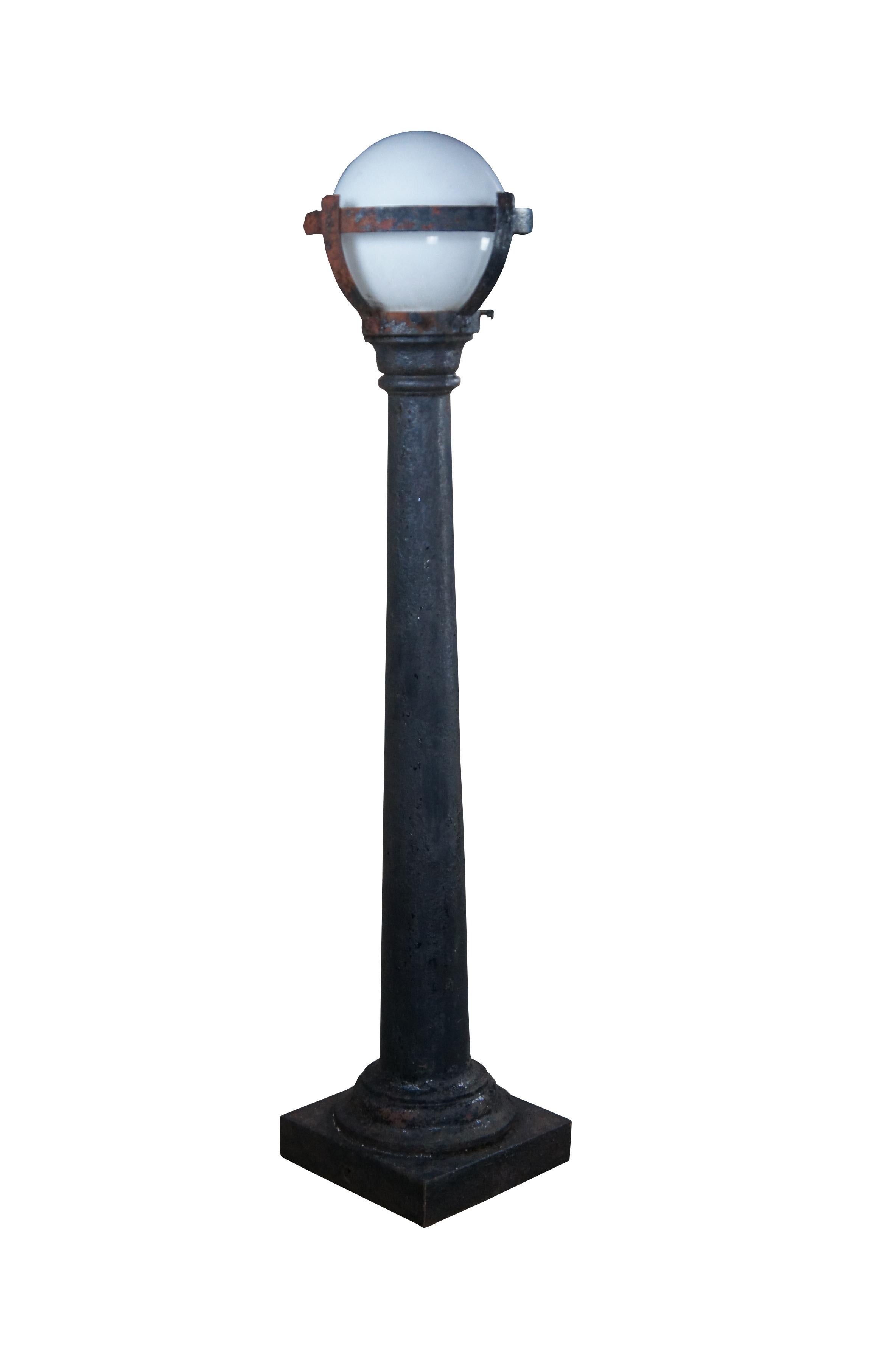 Antique Victorian industrial cast iron street post lamp or lantern featuring a square base with round tapered column and milk glass shade.
