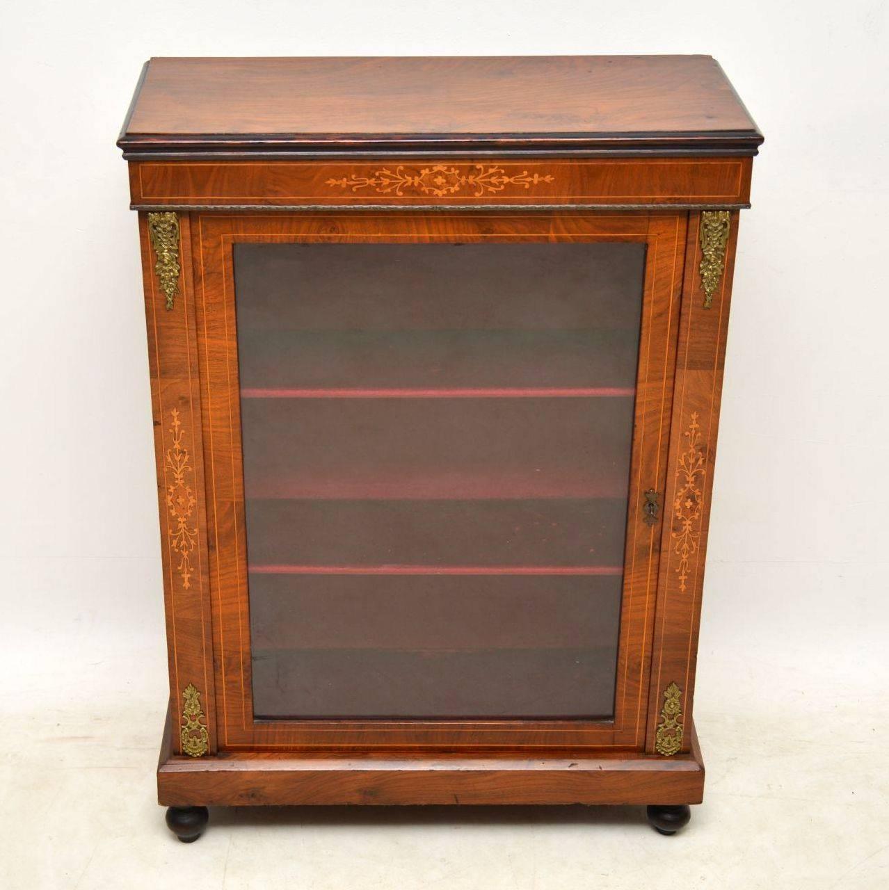 Antique Victorian figured walnut pier cabinet with some nice inlays and in good original condition. It has an ebonized top edge, a gilt metal beading and gilt metal appliqués top and bottom. The inside is lined and it sits on turned feet. These