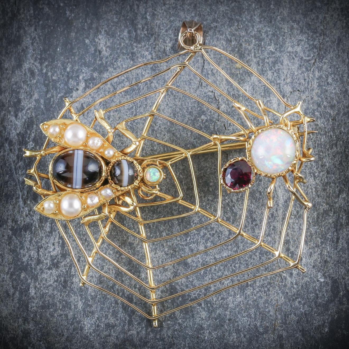 This enchanting antique insect brooch is Victorian Circa 1900

The fabulous piece depicts a fly and spider decorated with Garnets, Opals, Pearls and banded Agates on a 15ct Yellow Gold web.

The piece is fitted with a Gold loop as well as a sturdy