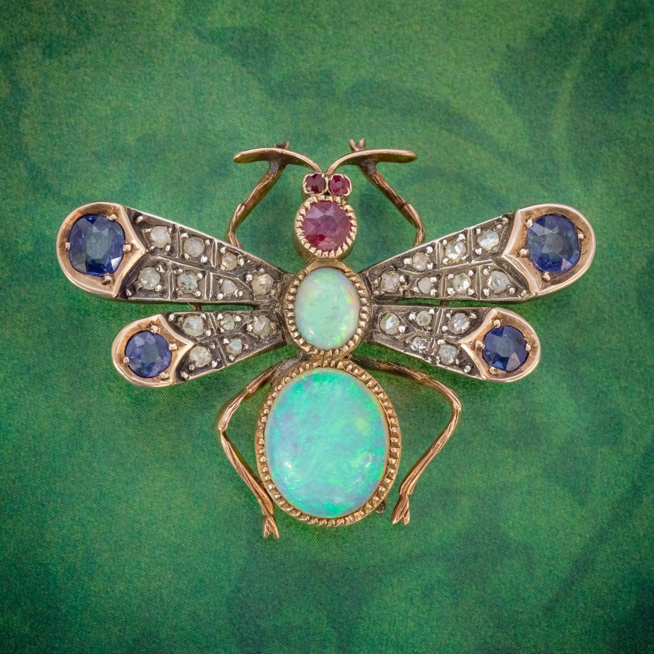 A fabulous Antique Victorian winged insect brooch boasting two colourful natural Opals set into the body, the smallest is approx. 0.75ct with the largest weighing approx. 4ct in the abdomen.

The head of the insect is set with rich red Rubies,