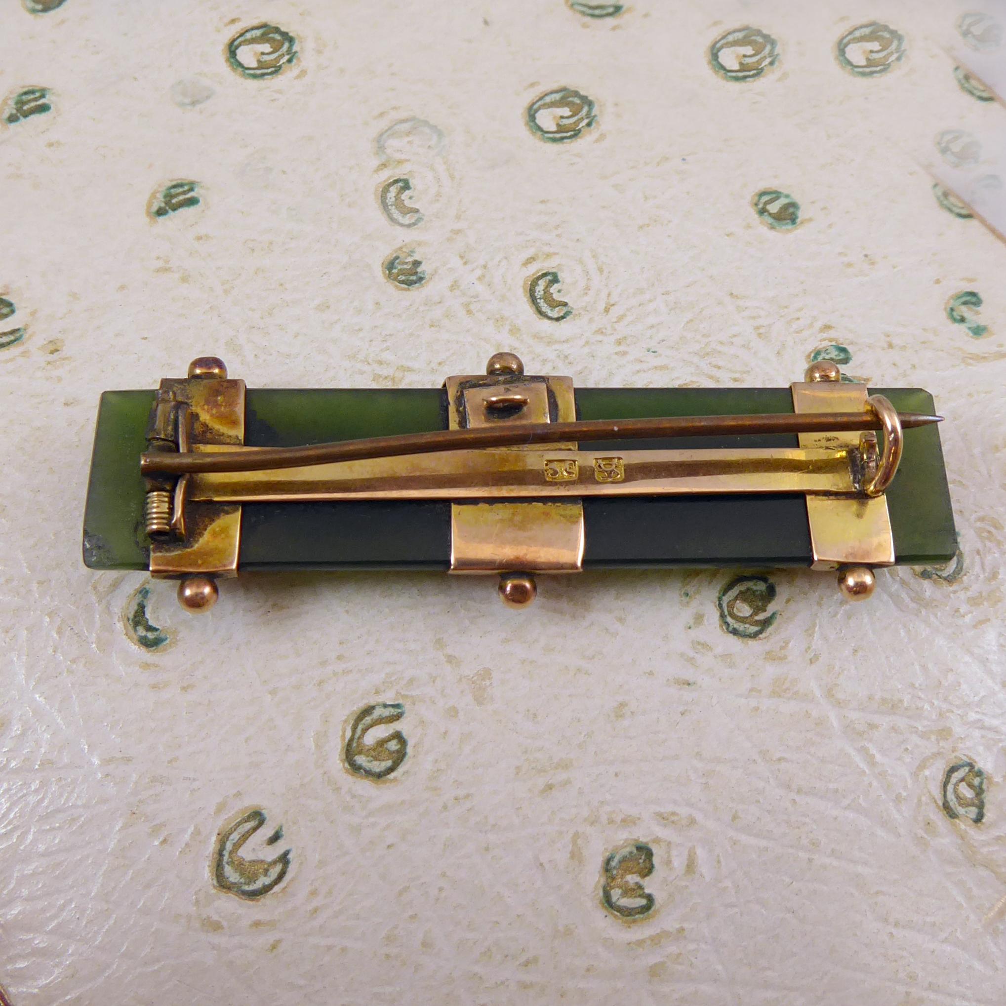 An antique jade brooch dating from the later Victorian era.  A D shaped cross sectioned slab of richly coloured jade the ends of which have been cut at an angle.  The jade features three rose gold straps the fronts of which are scalloped and