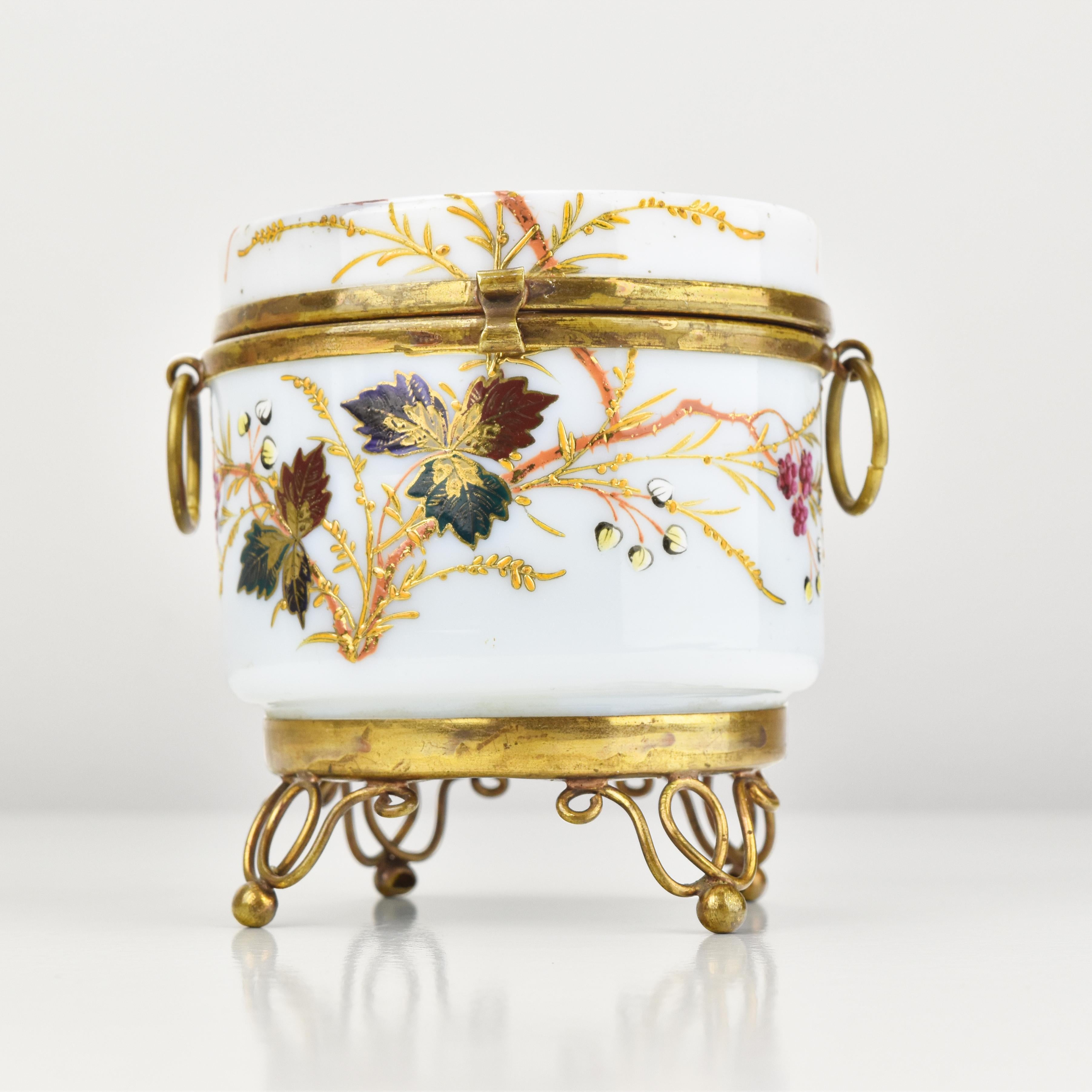 Diese antike viktorianische Opalglas-Schmuckschatulle ist ein echtes Zeugnis der Opulenz und Eleganz dieser Epoche.

Das Prunkstück ist zweifellos die exquisite florale Emaillemalerei, die die Oberfläche mit kunstvollen Details und leuchtenden