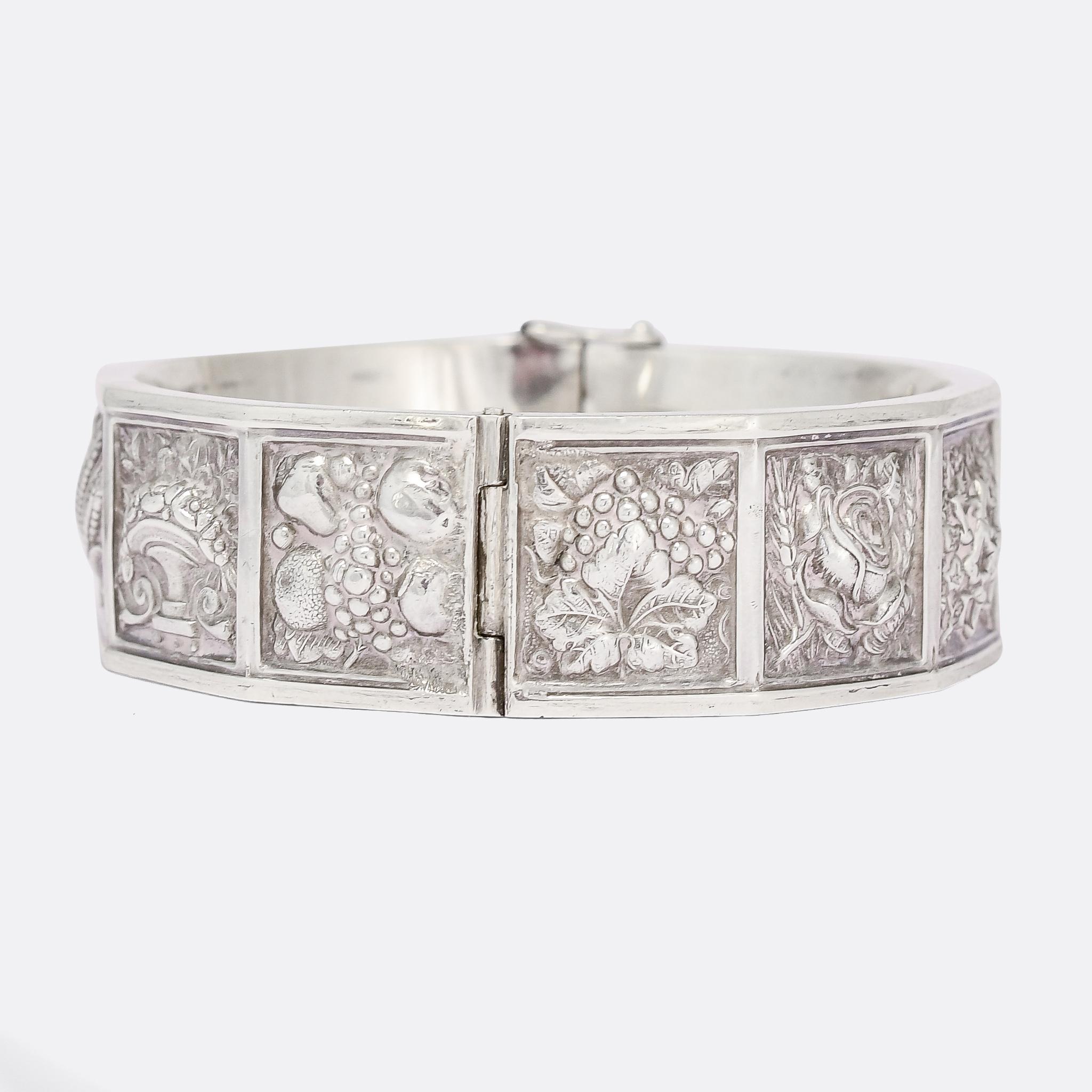 A gorgeous Victorian cuff bangle featuring twelve square panels, each one adorned with a high relief depiction of a flower or plant. The Victorians created a secret 