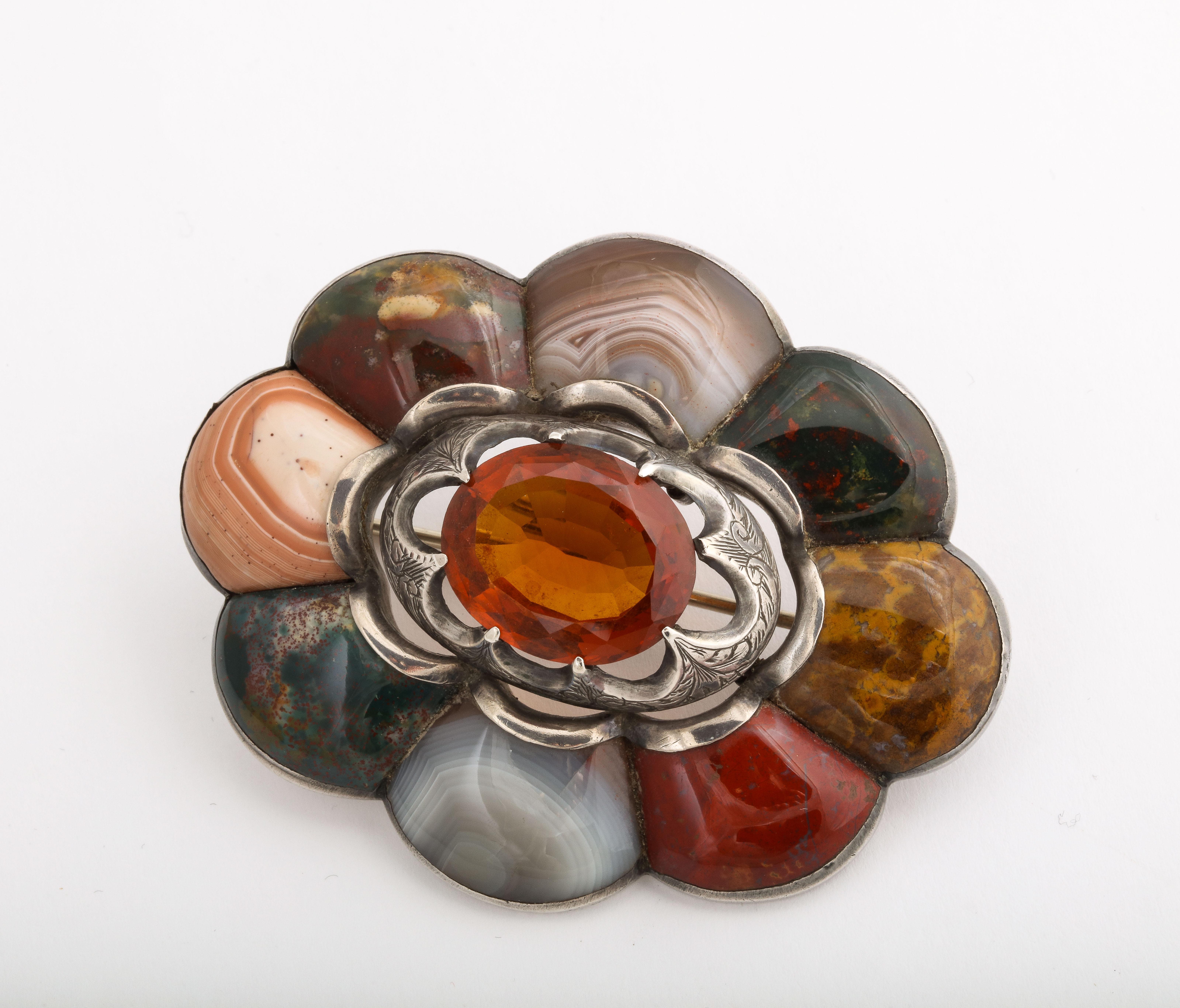 The agates in this Scottish Brooch are like a patchwork of specimen stones. There is peach banded agate, moss agates, montrose agate mustard agate and bloodstone. The brooch is large at 2 1/2 in width and 2 inches high. An oval citrine is the target