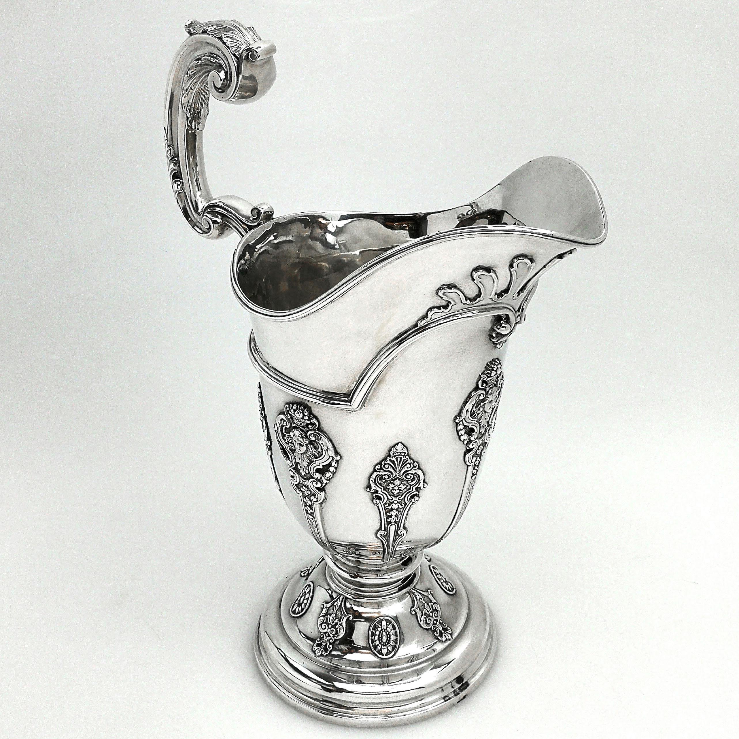 A magnificent Antique Victorian solid Silver Jug with a magnificent everted spout. The Pitcher stands on a side pedestal foot and has an impressive acanthus leaf scroll handle. The body of the Jug and pedestal foot are both decorated with intricate