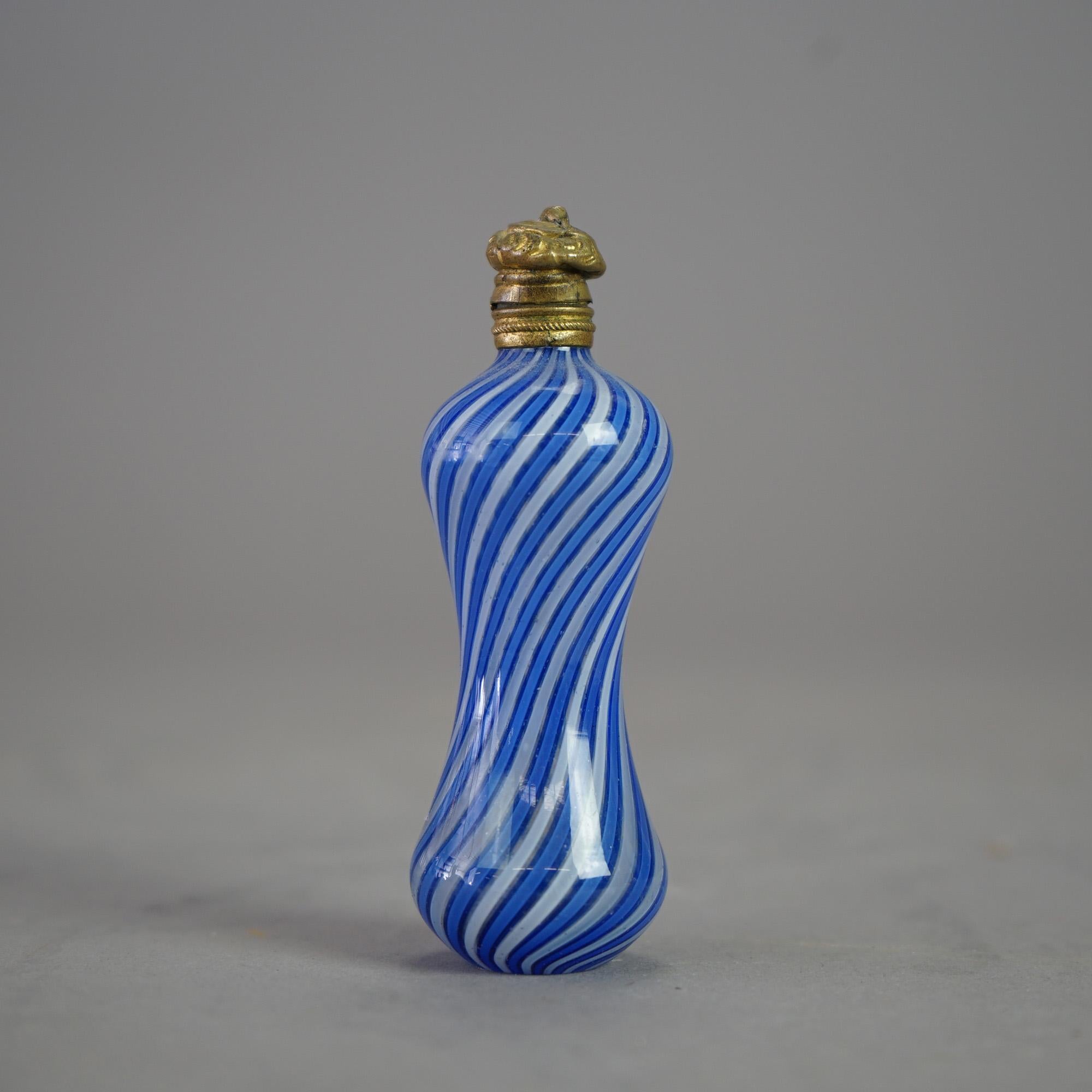 An antique Victorian Latticino perfume offers blue and white swirl art glass construction in hourglass form having a foliate embossed cast flip-top lid, 19th century

Measures- 3''H x 1.25''W x 1.25''D