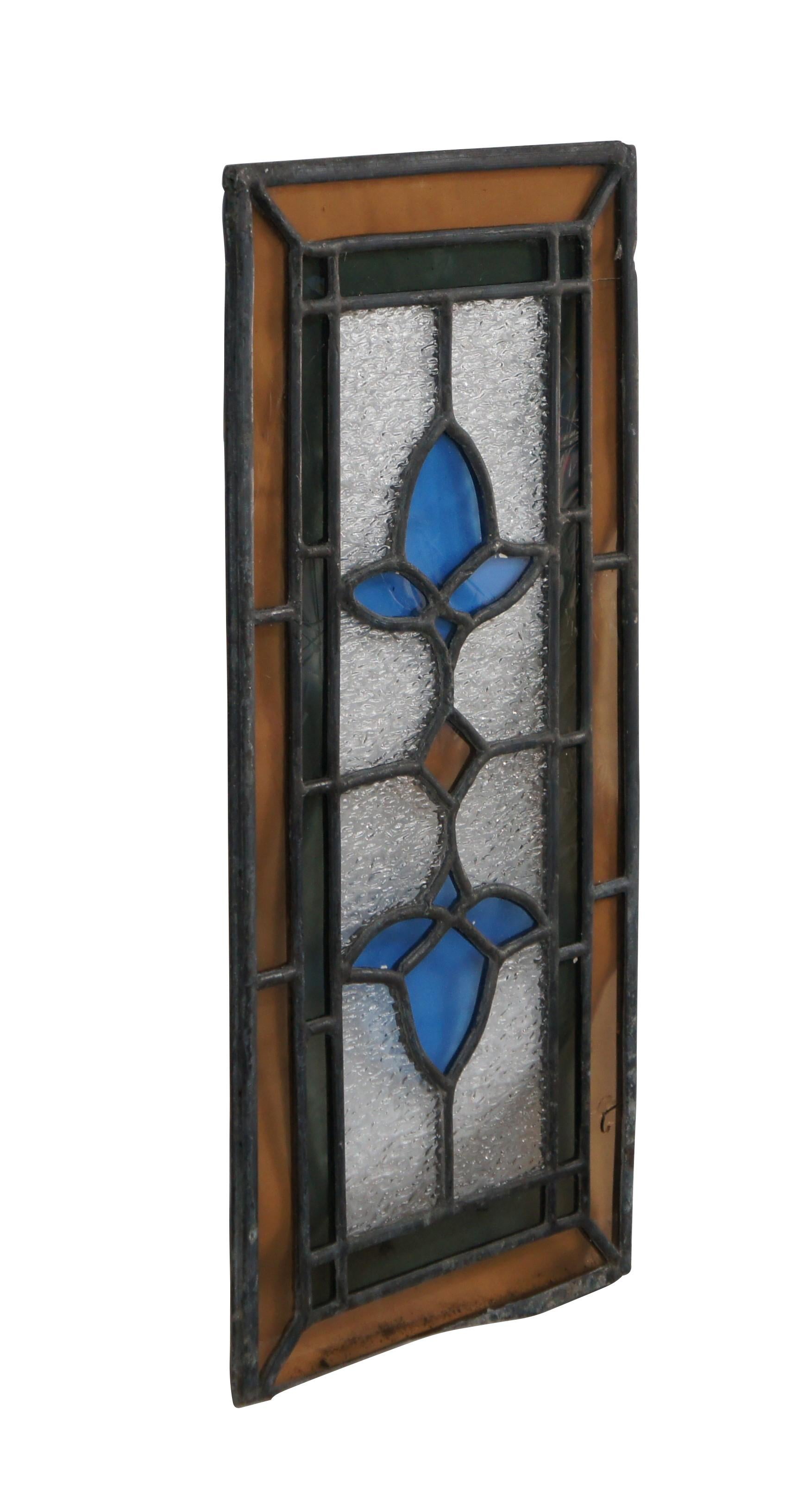Antigua vidriera emplomada recuperada. Presenta un diamante en el centro compensado por dos rosas azules. La ventana está enmarcada con un borde ámbar fuera de un borde tintado de verde.

Dimensiones:
17