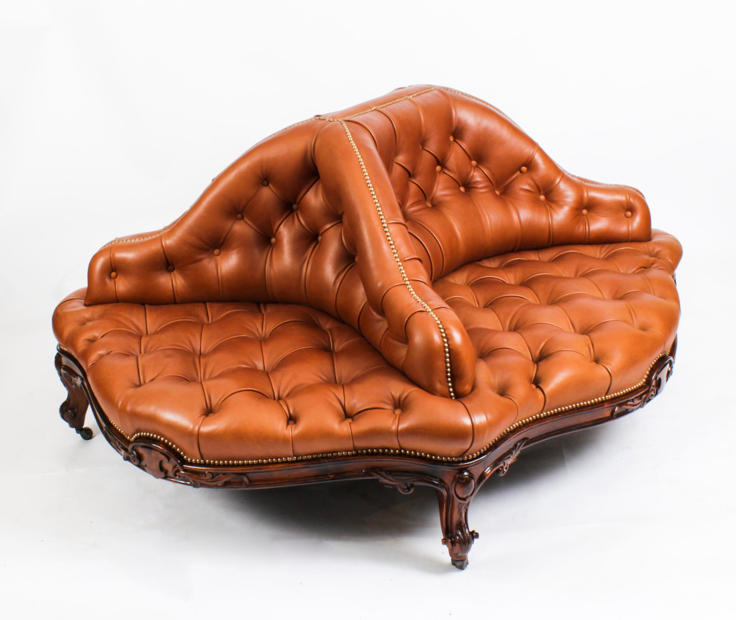 This is a very large fantastic English antique early Victorian walnut and leather framed conversation seat, also known as a 