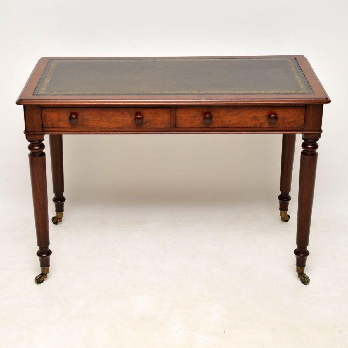 This antique Victorian leather top mahogany writing table is in good condition & dates to around the 1860-1880s period. It has a tooled leather writing surface, two drawers on the front with turned mahogany handles and a polished finished back. This