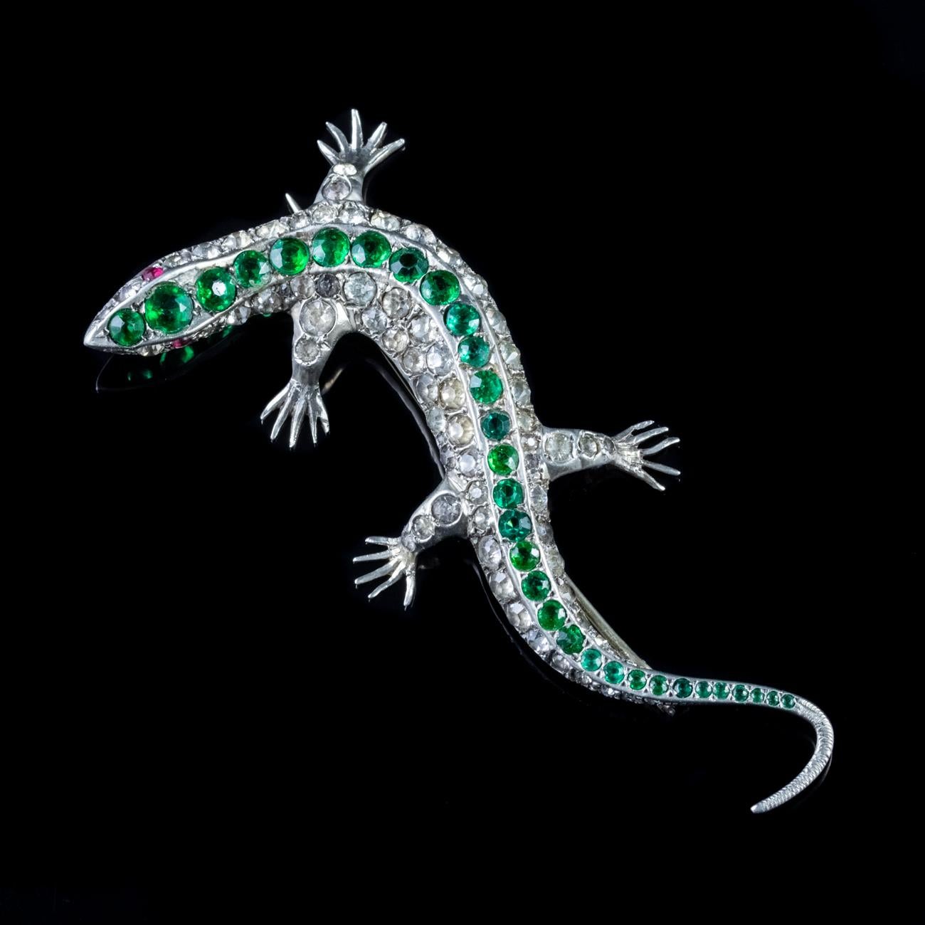 A fabulous Antique Victorian brooch modelled in Sterling Silver, depicting a colourful lizard decorated with stripes of old cut emerald green and white Pastes Stones down the back and red Paste eyes. 

Victorian jewellery mirrored Queen Victoria’s