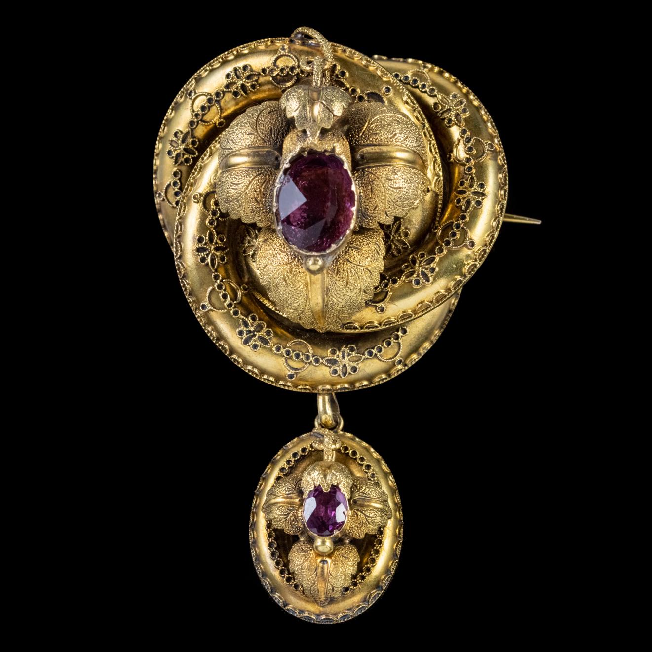 A stunning Antique Victorian brooch depicting a decorative lovers knot crowned with beautiful high relief leaves and a violet Paste stone. A dropper also swings from the gallery in the same style and topped with a natural Amethyst. 

A lover’s knot