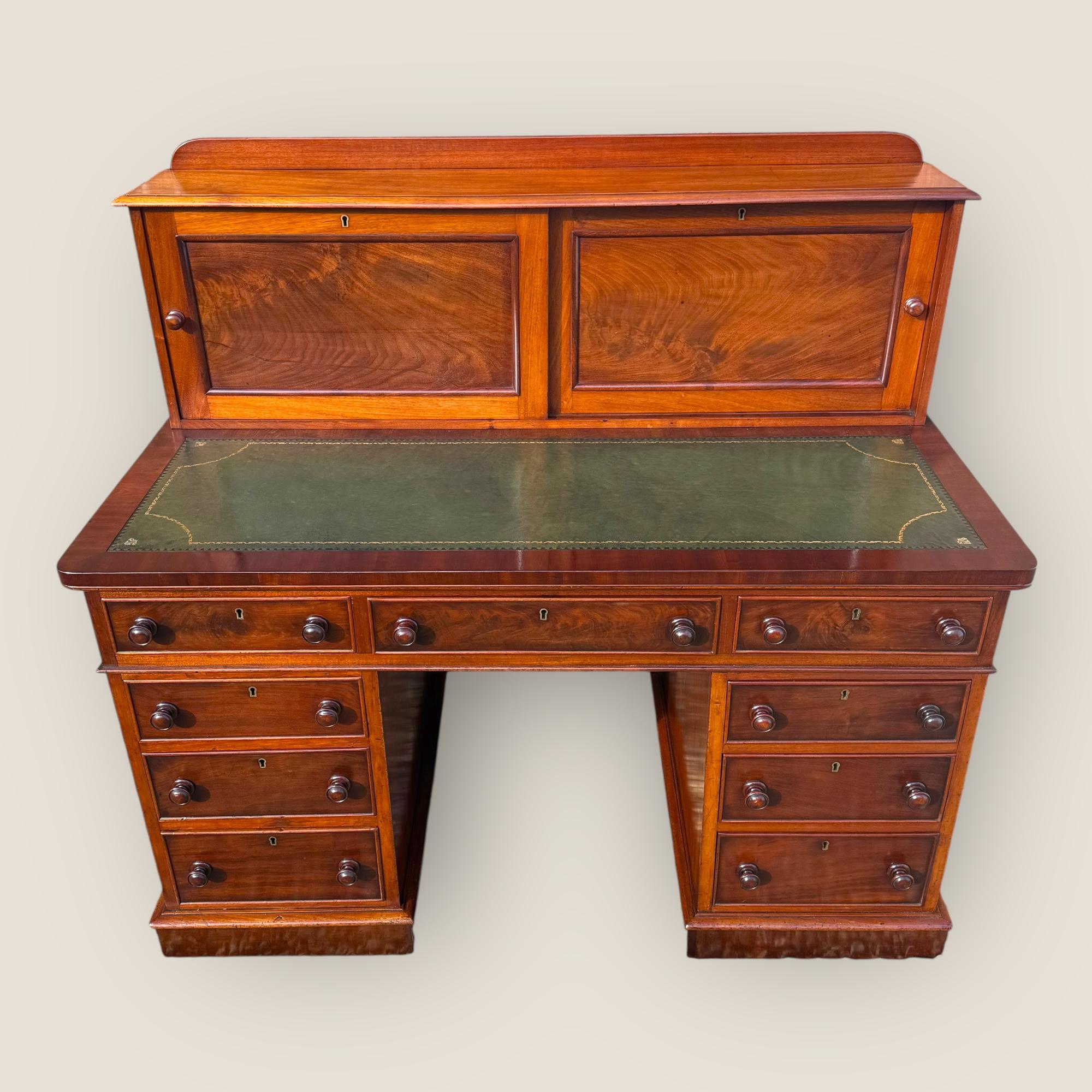 Qui abbiamo un'antica scrivania a piedistallo a 9 cassetti in mogano di epoca medio-vittoriana (1850-1870) con un armadio a ante scorrevoli nella parte superiore. A questa bellissima scrivania è stata applicata una nuova pelle verde di ricambio, con
