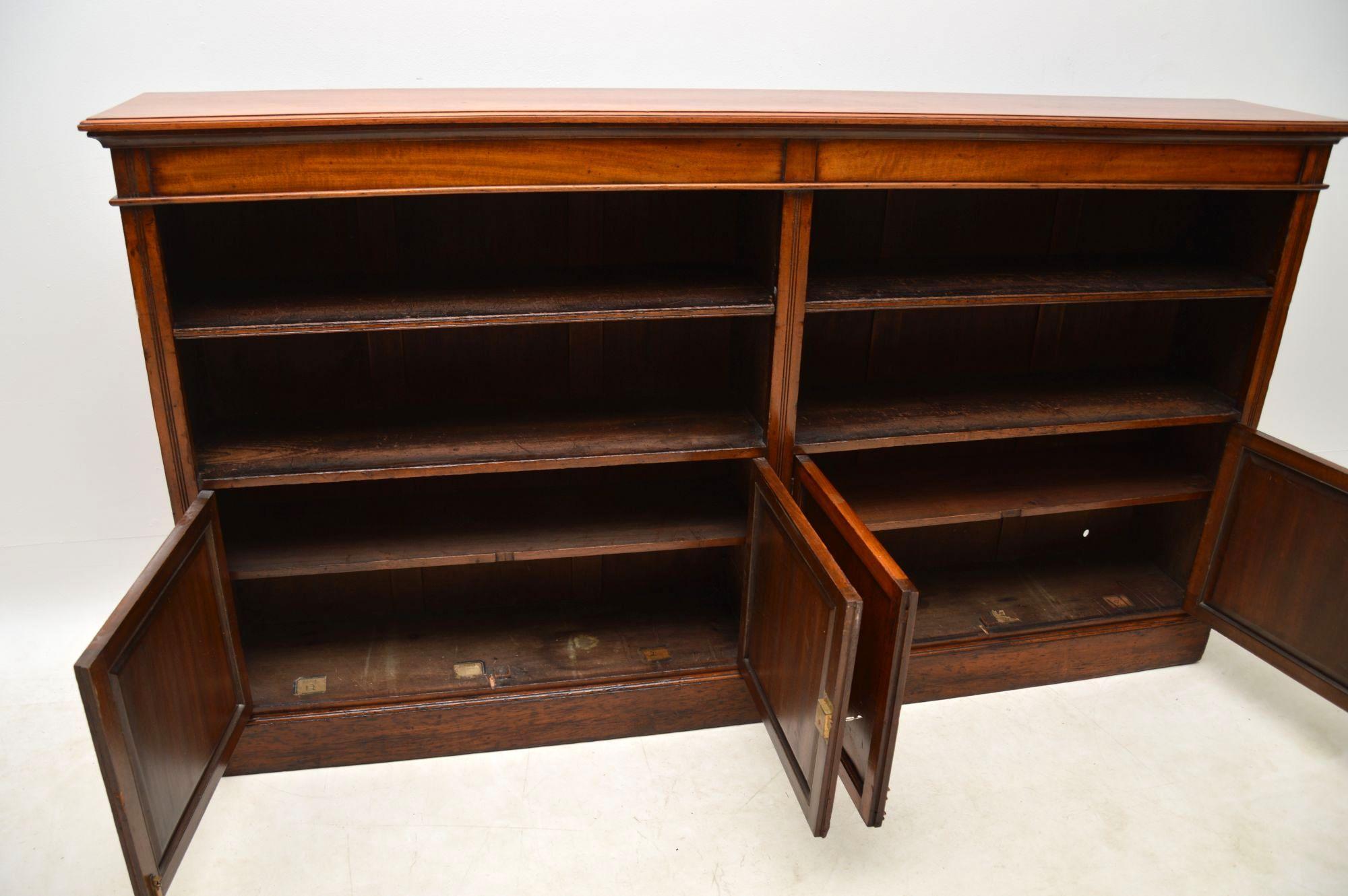 Long solid mahogany antique Victorian bookcase cabinet in good original condition with loads of character and dating to circa 1880s period. It’s a very solid looking item and is very well made. The two open sections have one adjustable shelf in