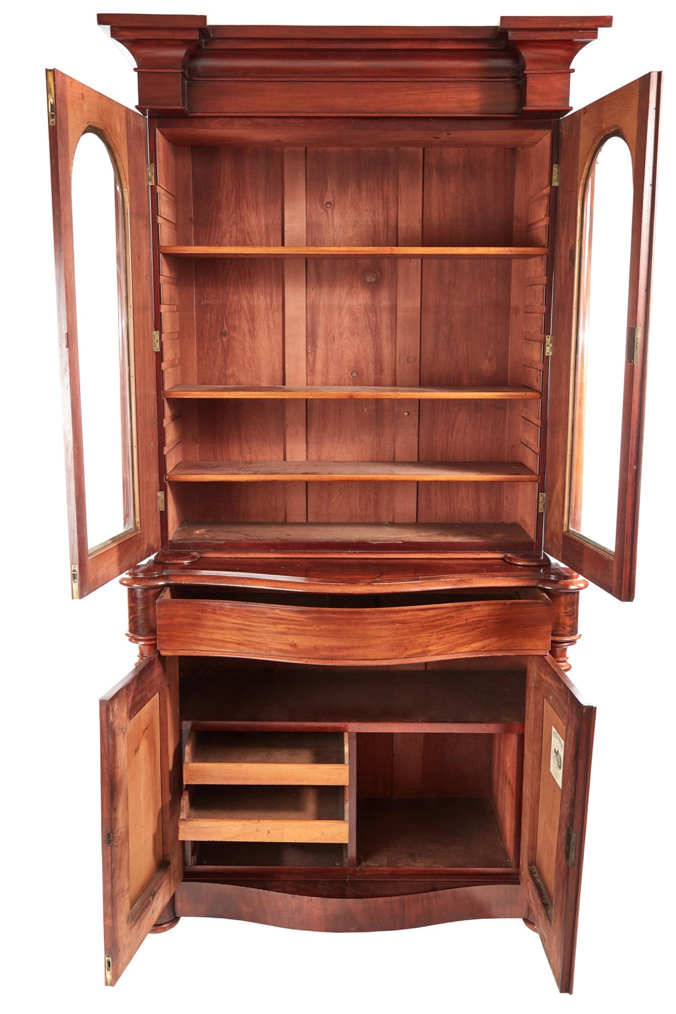 This is a quality 19th century Victorian antique mahogany bookcase. The upper section having an attractive shaped cornice over a pair of glazed doors with shaped mouldings and turned columns. The doors open to reveal an interior with adjustable