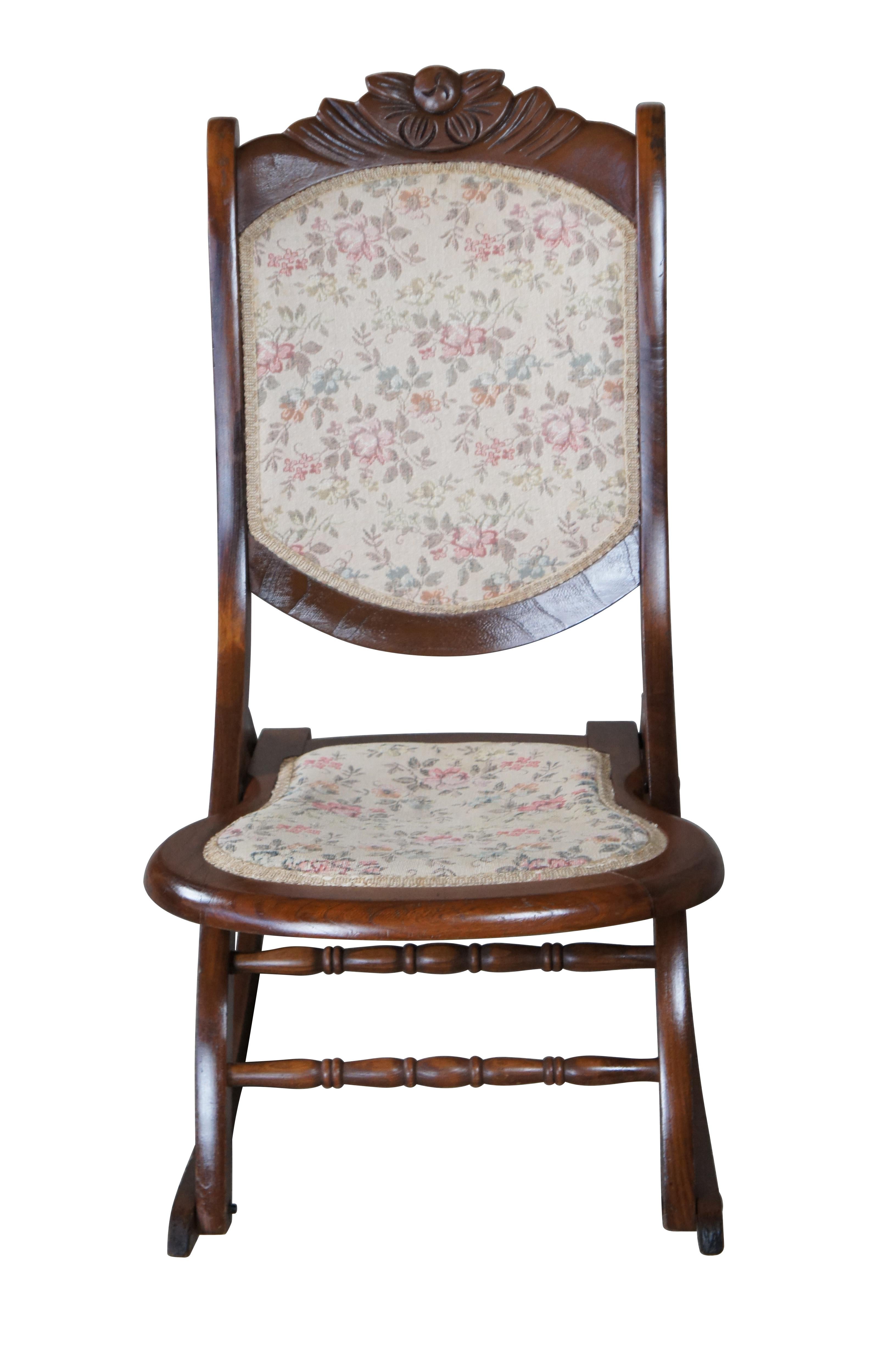Victorian era folding rocker. Features a floral carved crest rail and a cream rose patterned upholstery.

Dimensions:
29