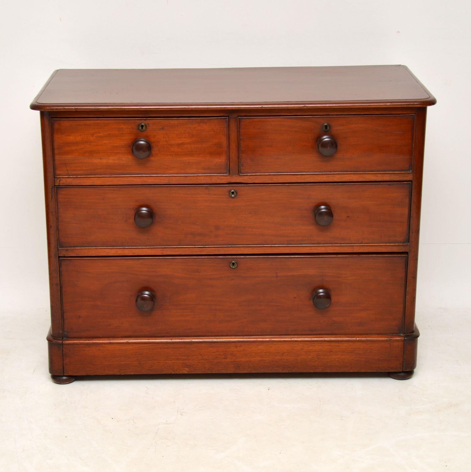 This antique Victorian mahogany chest of drawers has nice proportions, being a bit lower & wider than most. It has a solid mahogany top, original mahogany bun handles and sits on a plinth base with flat bun feet below. The locks and escutcheons are