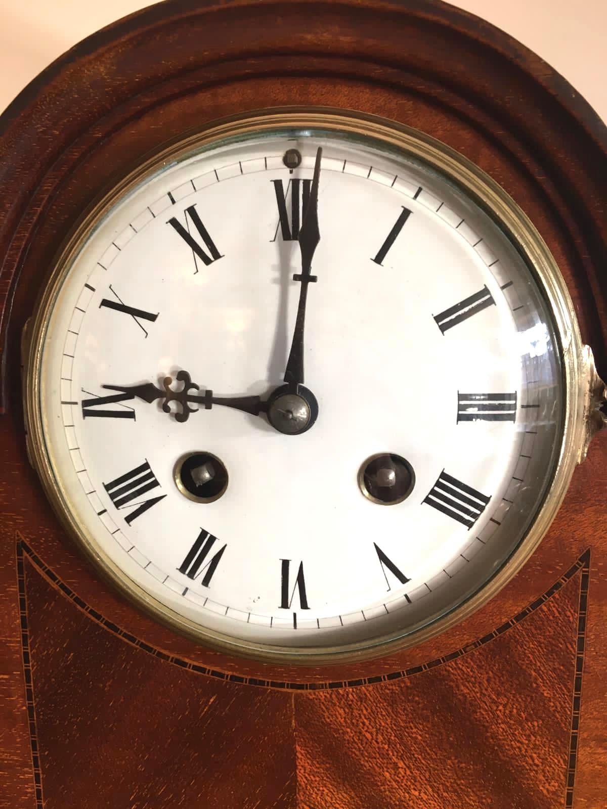 Antique Victorian mahogany desk clock having an 8 day striking movement with enamel dial, original hands and pretty dome top mahogany case. It boasts elegant turned columns to the corners with three lovely inlaid panels to the front, it stands on a