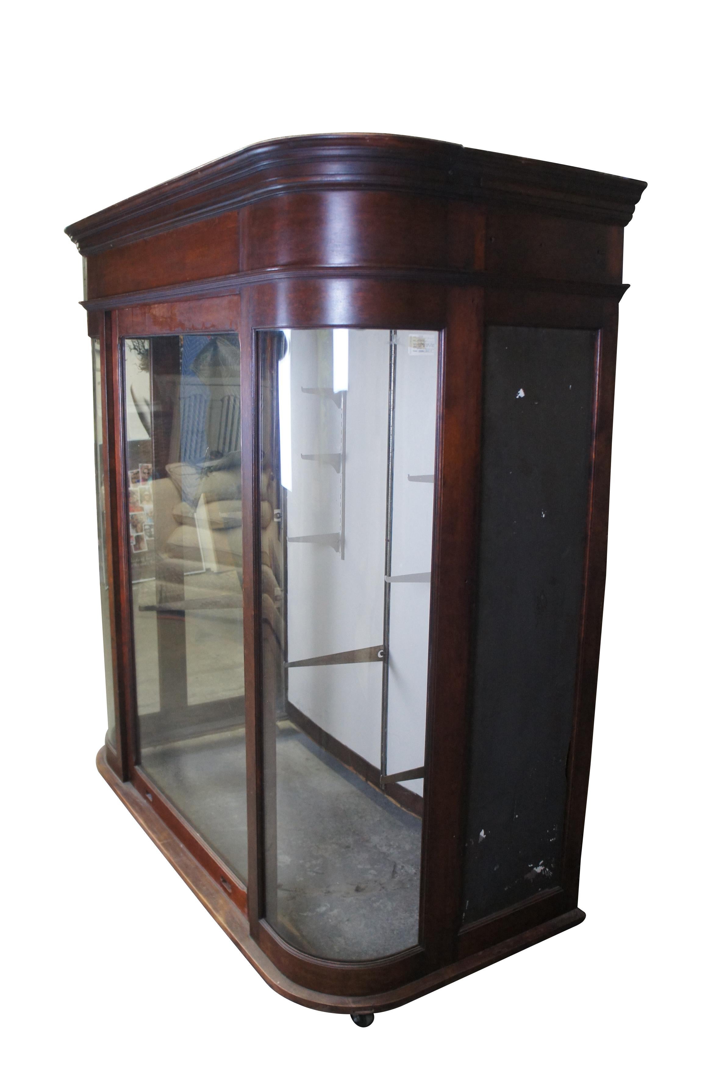 Monumental Victorian general store / apothecary display cabinet. Made from mahogany with curved glass and a large weight driven door that extend through the top. Most recently used at a tire shop in Xenia Ohio.  This cabinet would be most impressive