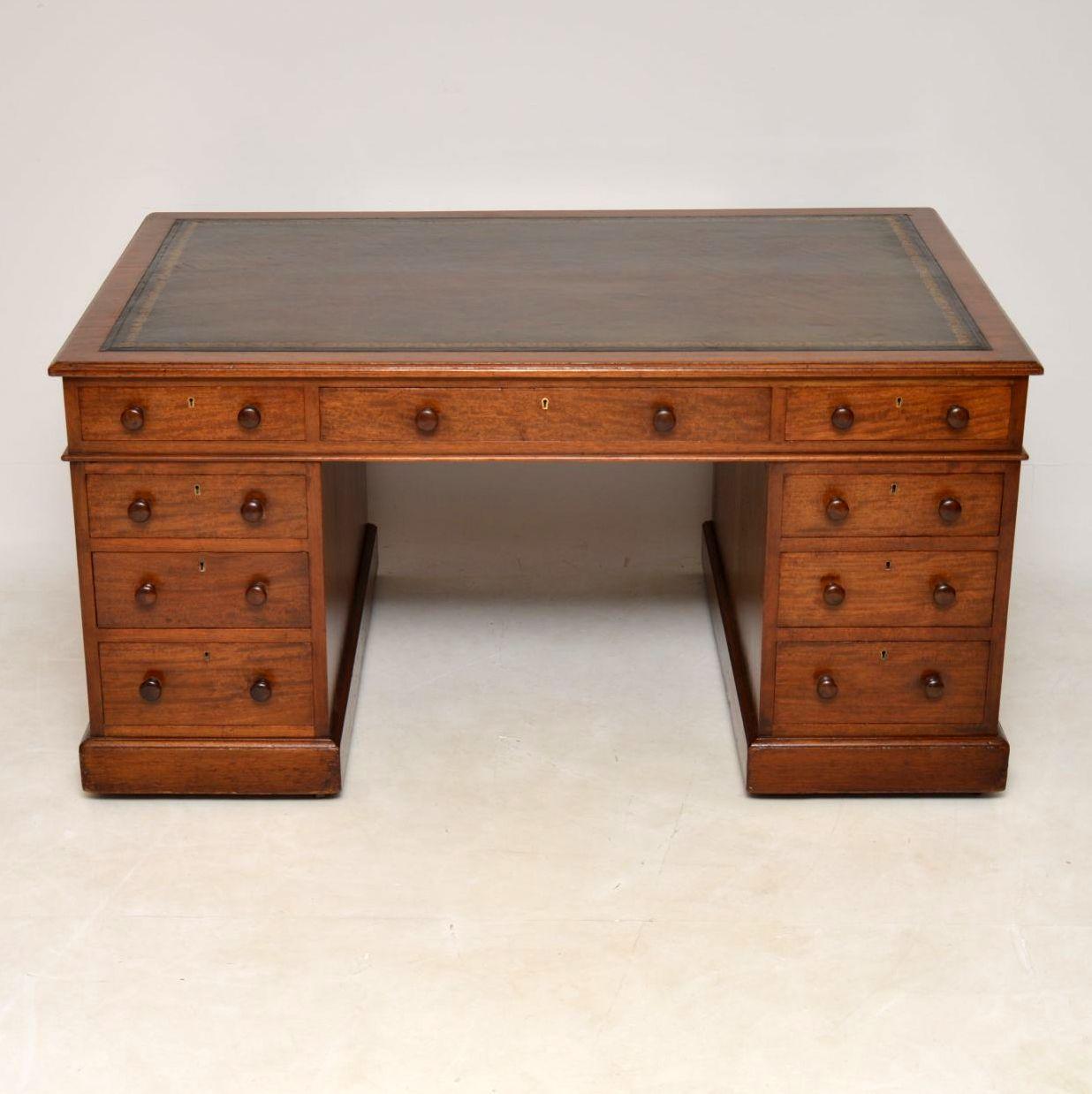 This antique Victorian mahogany partners desk is nice quality and in excellent condition. It has a hand colored tooled leather writing surface and sits on bracket feet with casters underneath. There are drawers on the top front and back. Drawers on