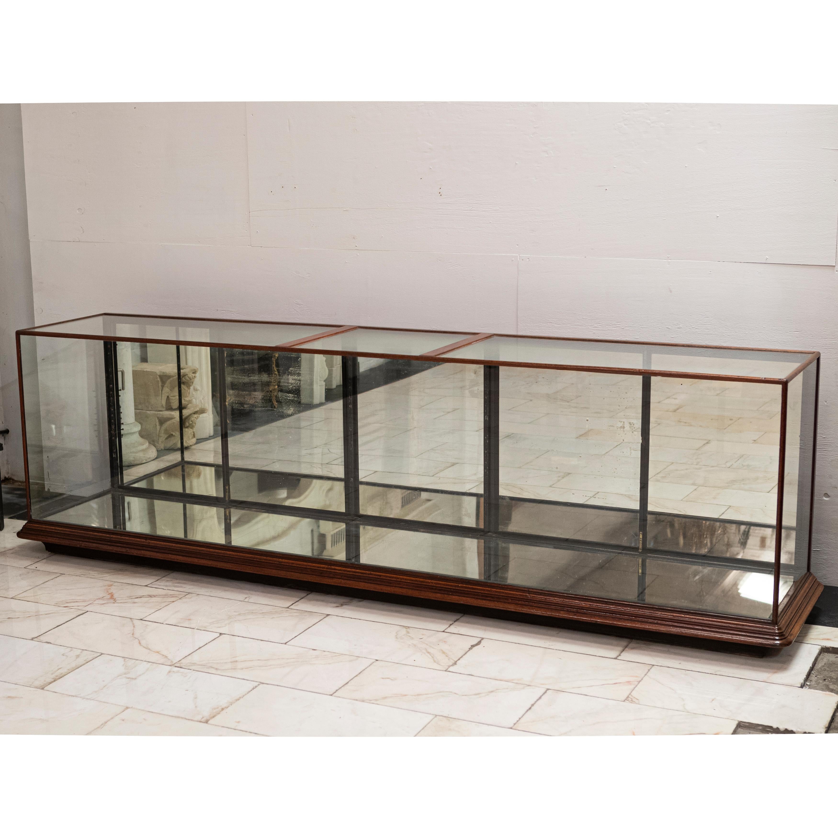 Esta gran e impresionante vitrina está hecha de caoba con laterales y parte superior de cristal.

El mueble original del siglo XIX tiene 2 juegos de puertas de armario dobles y la sección central es sencilla. Las puertas de los armarios tienen un
