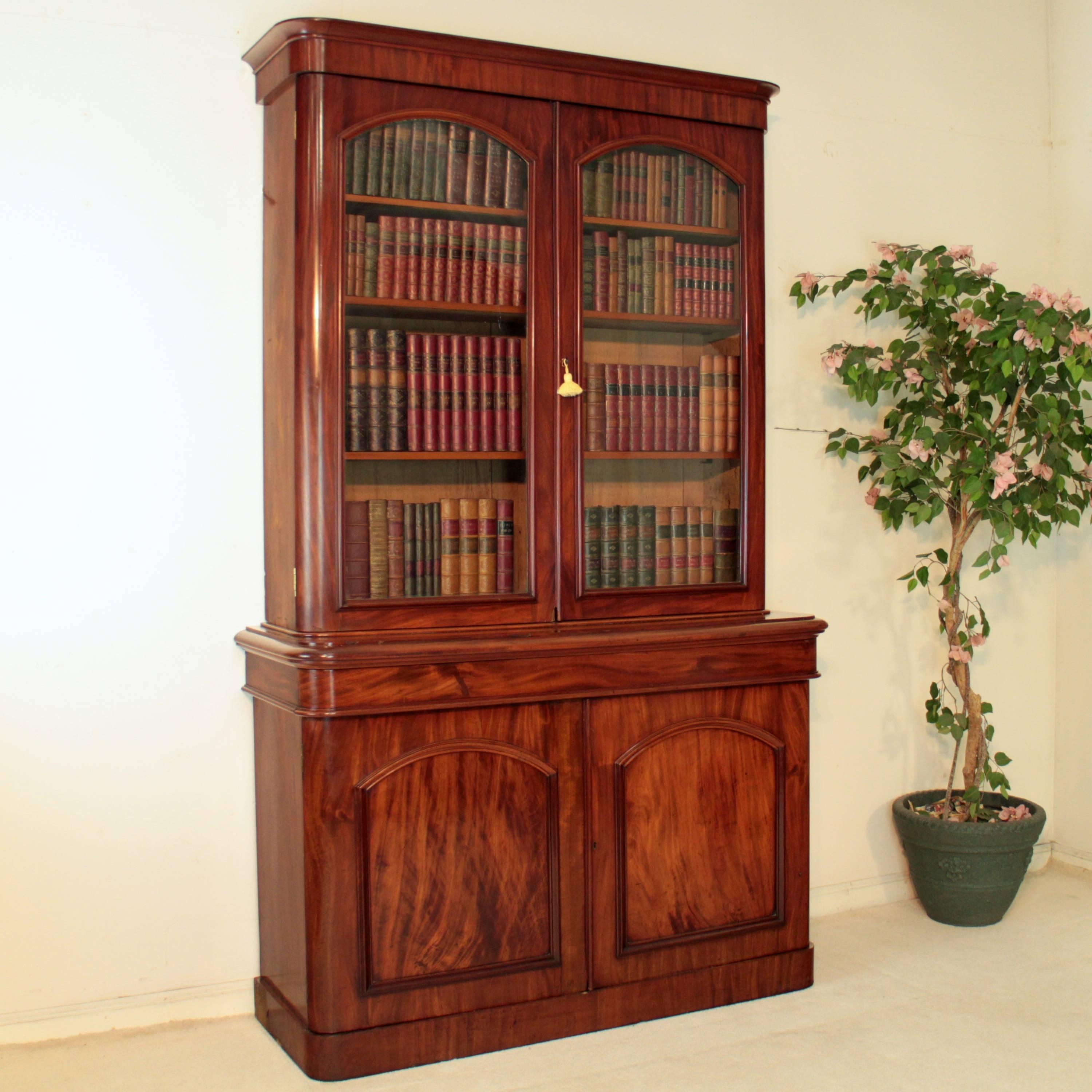 An attractive Victorian mahogany bookcase dating to circa 1870, with a moulded cornice above a pair of glazed doors enclosing three adjustable shelves, the projecting base with a concealed drawer and two panelled cupboard doors, all standing on a