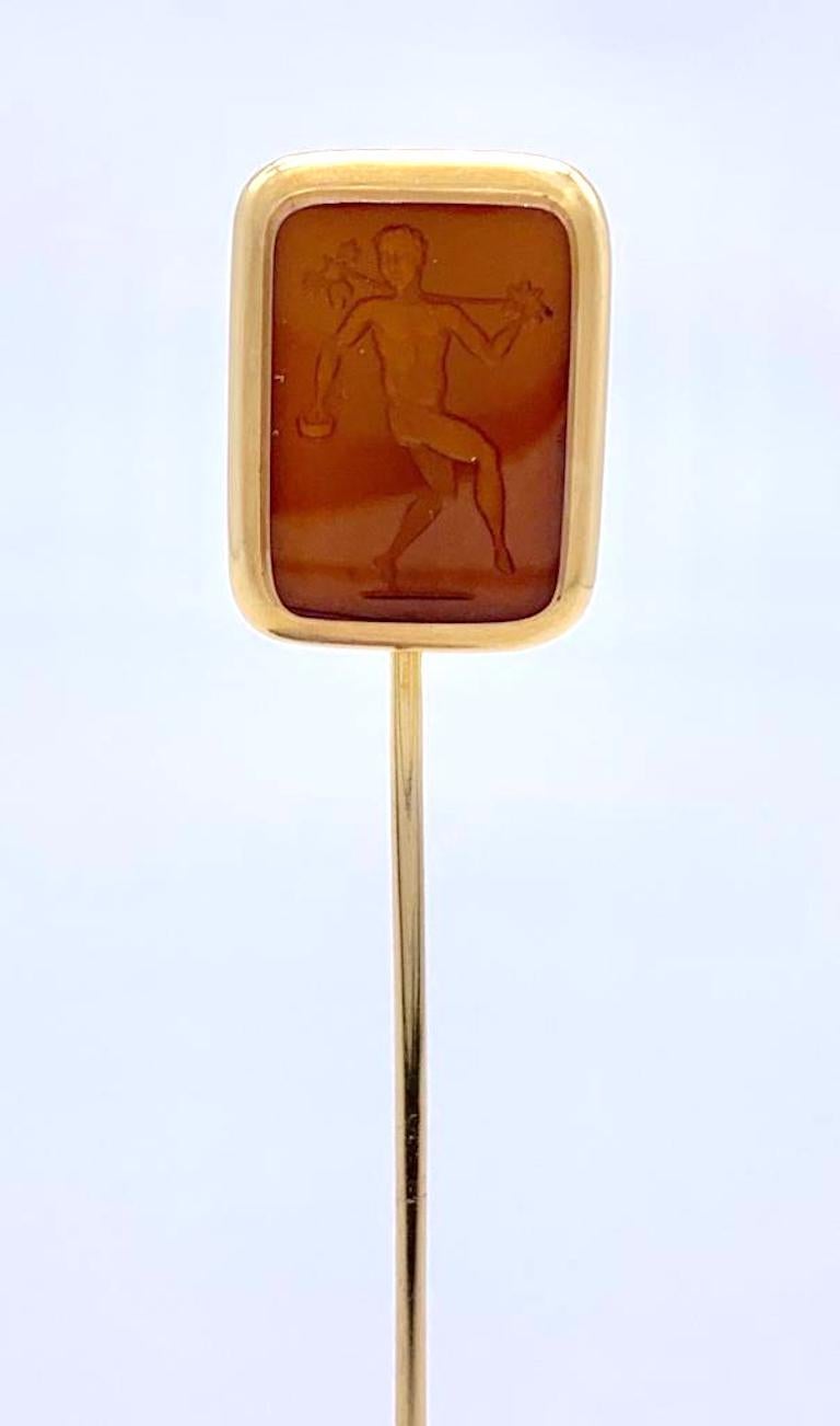 Elegant French stick pin with an agate intaglio depicting a follower of Bacchus or Dionysos. The carving represents a naked young man carrying a grape vine over his left shoulder and a tambourine in his right hand. He is represented in a dancing