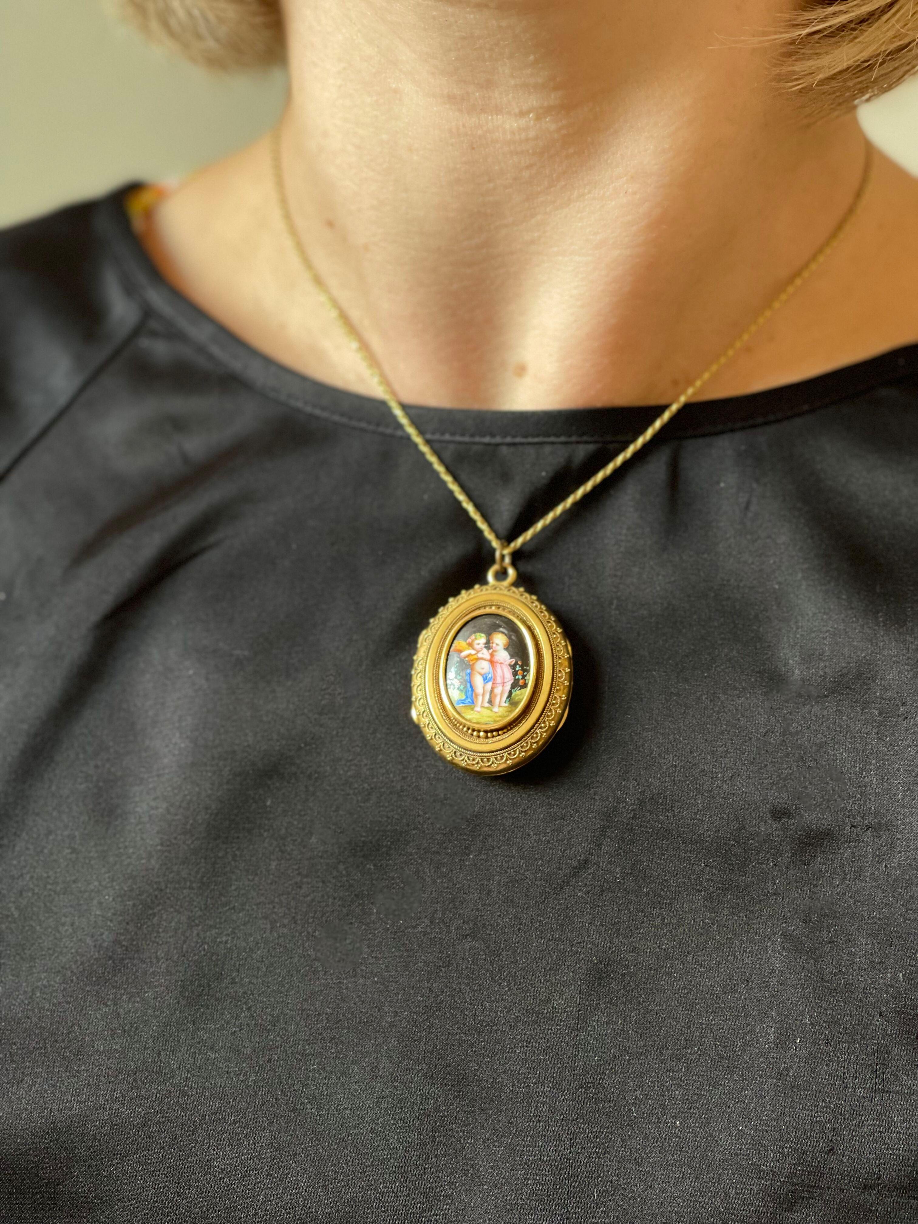 Antique Victorian 14k gold pendant locket, decorated with hand painted miniature painting, depicting two cherubs. The locket has the original antique photograph of a gentleman inside. Measures 1 5/8