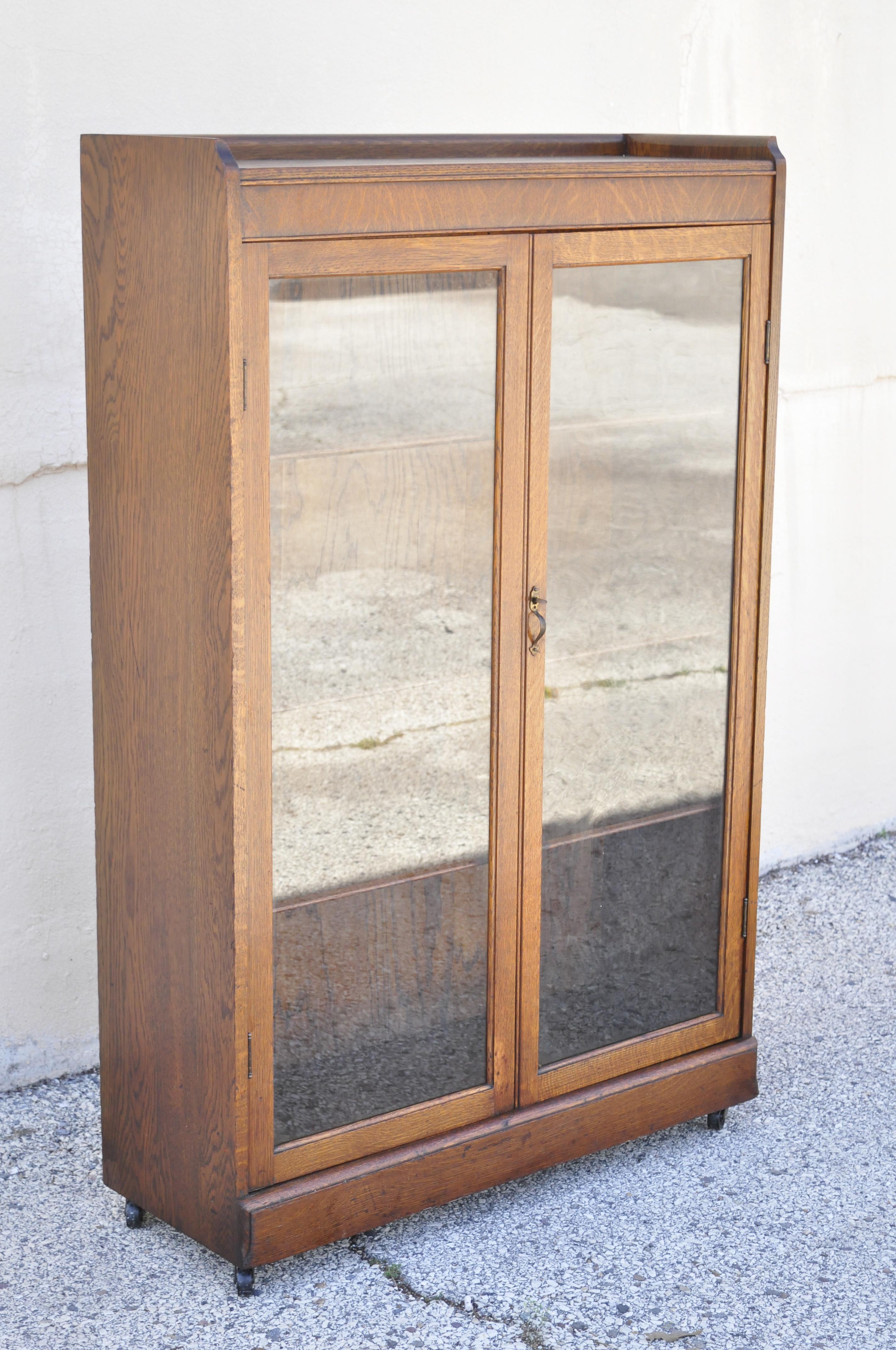 Antique Victorian Mission oak glass two door small bookcase curio cabinet. Item features beautiful wood grain, 2 glass swing doors, original label remnants, 4 wooden shelves, very nice antique item, quality American craftsmanship, great style and