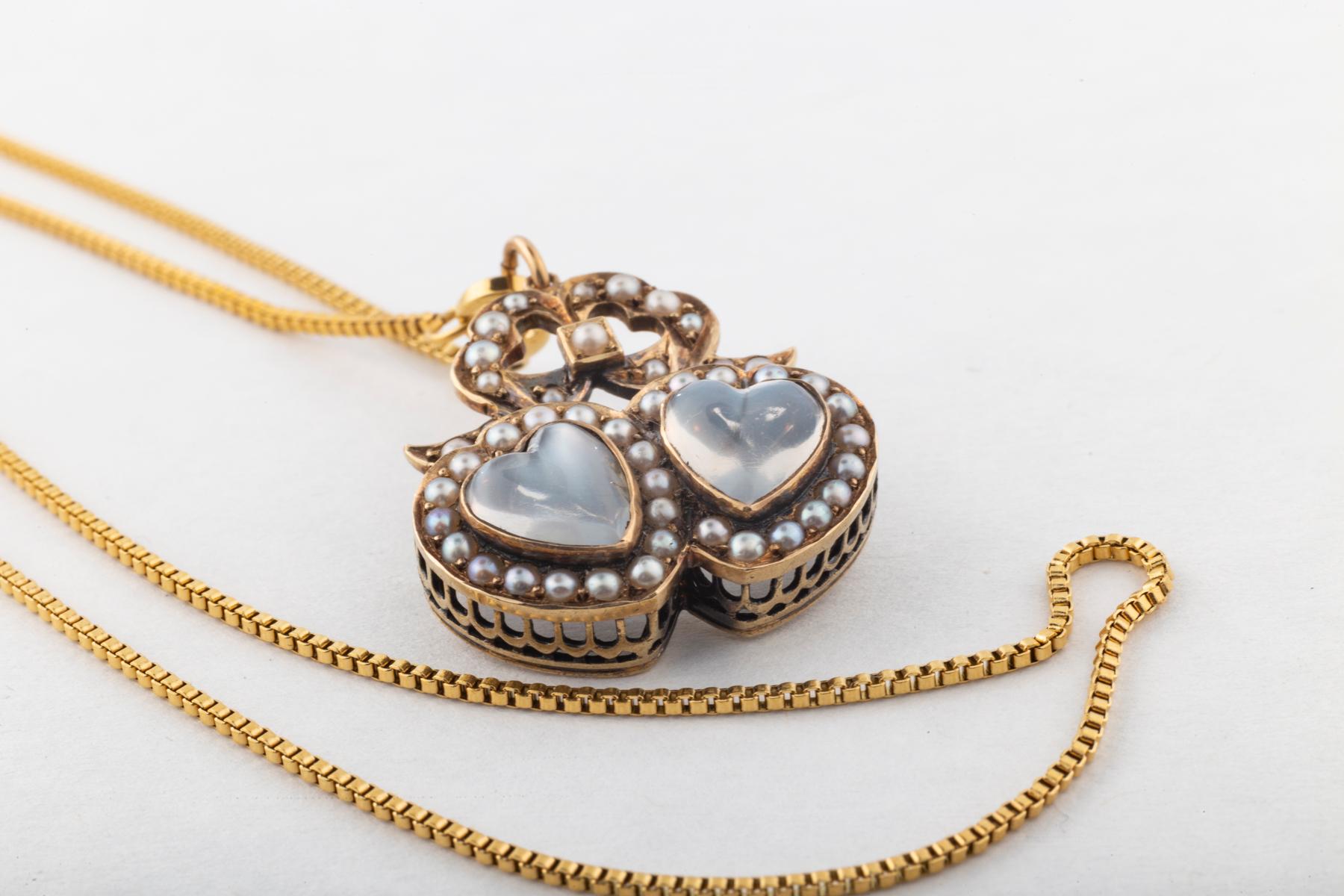 A brooch with a pendant loop allows this moonstone double heart and pearl jewel to be worn as you choose. On top of the hearts, like a crown is a pearl bow which sends the message 
