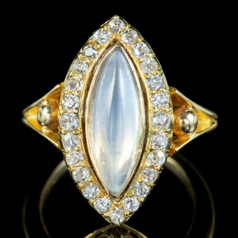 An exquisite antique Navette ring from the mid Victorian era crowned with a wonderful navette shaped moonstone with a ghostly, blue glow. It weighs approx. 2.20ct and is framed in a border of twenty-four old mine cut diamonds totalling approx. 1ct.