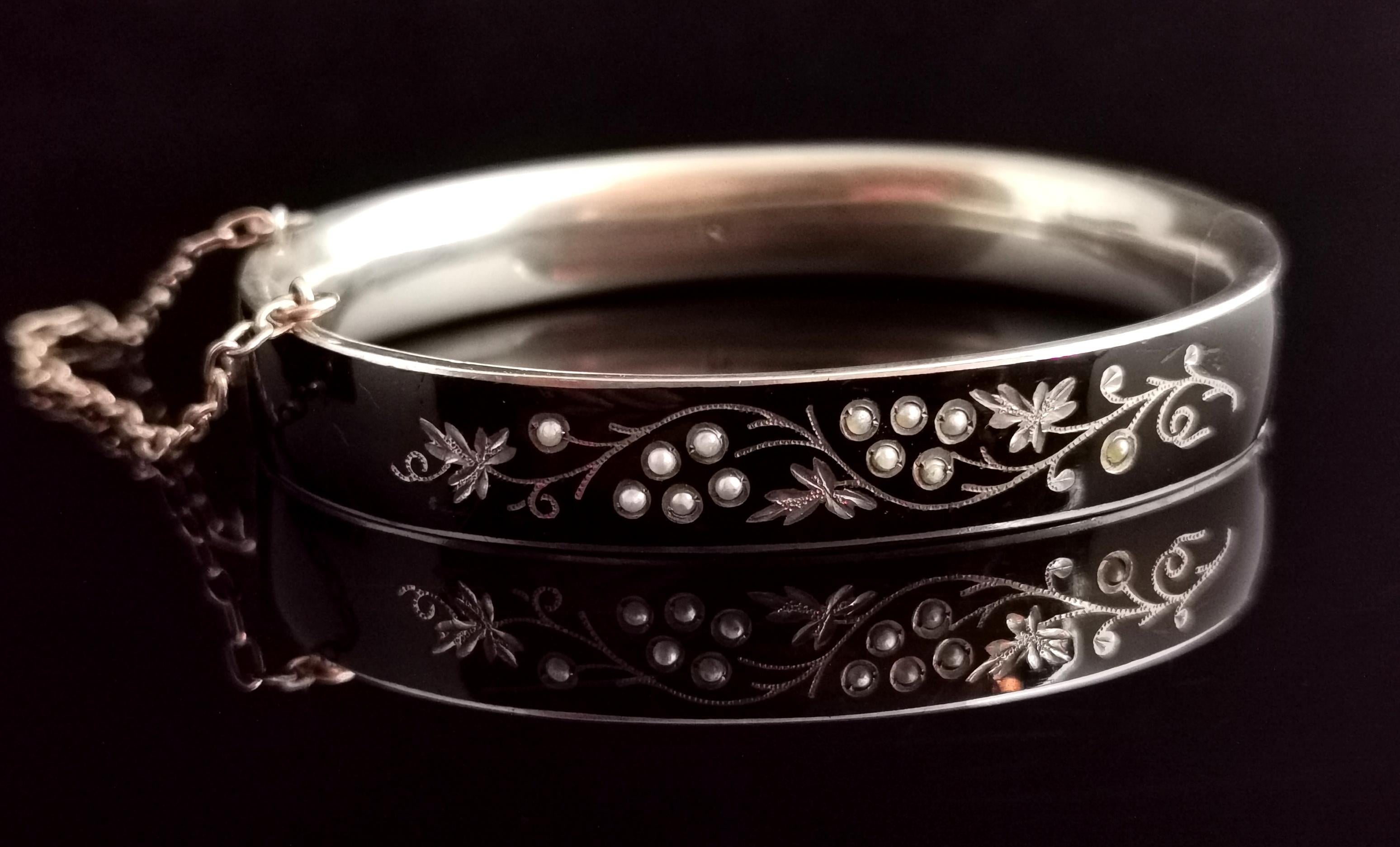 A beautiful antique, late Victorian mourning bangle.

It is made from silver and enamelled black, set with seed pearl to the front with an engraved grape vine design.

Possibly Austro Hungarian it is marked with an N, tests as sterling silver.

It