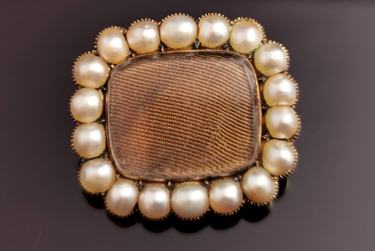 A beautiful antique Victorian mourning brooch.

Early to mid Victorian this brooch is a rounded rectangular shape with a glazed front compartment enclosing very tightly woven light brown hair.

It has a border of creamy split pearls and is set in