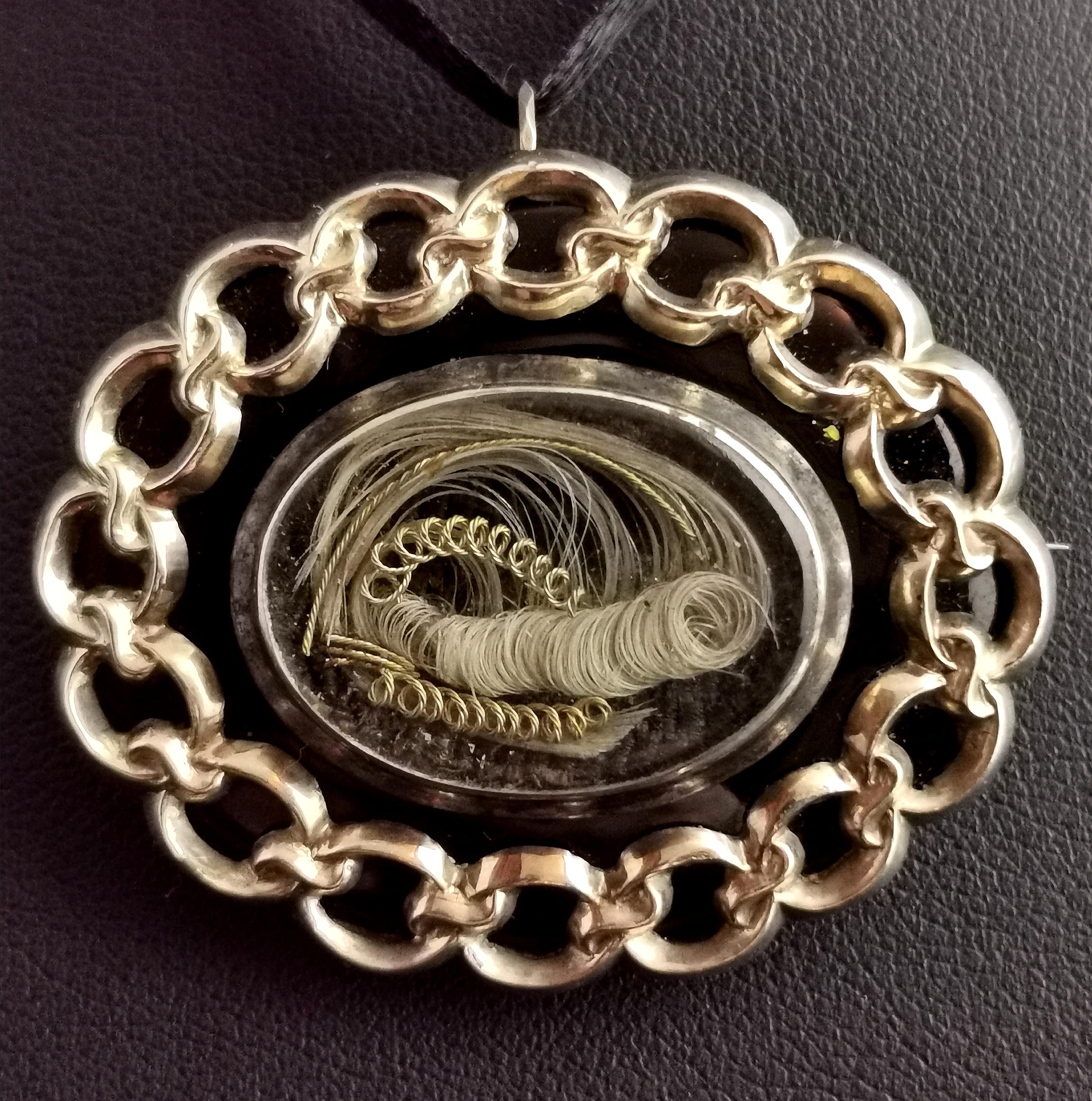 A stunning antique Victorian mourning pendant brooch, a beautifully made piece that is full of sentiment.

It is an oval shaped brooch in 9kt yellow gold with a central glazed panel with a hairwork section holding a stylised lock of blonde hair with