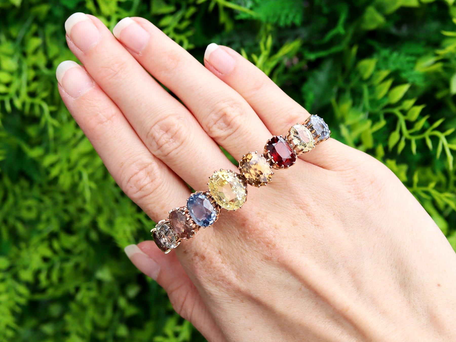 This stunning, fine and impressive antique gemstone bangle has been crafted in 9k yellow gold.

The anterior portion of this Victorian bangle is embellished with a linear array of nine claw-set oval faceted cut gemstones, graduating in size