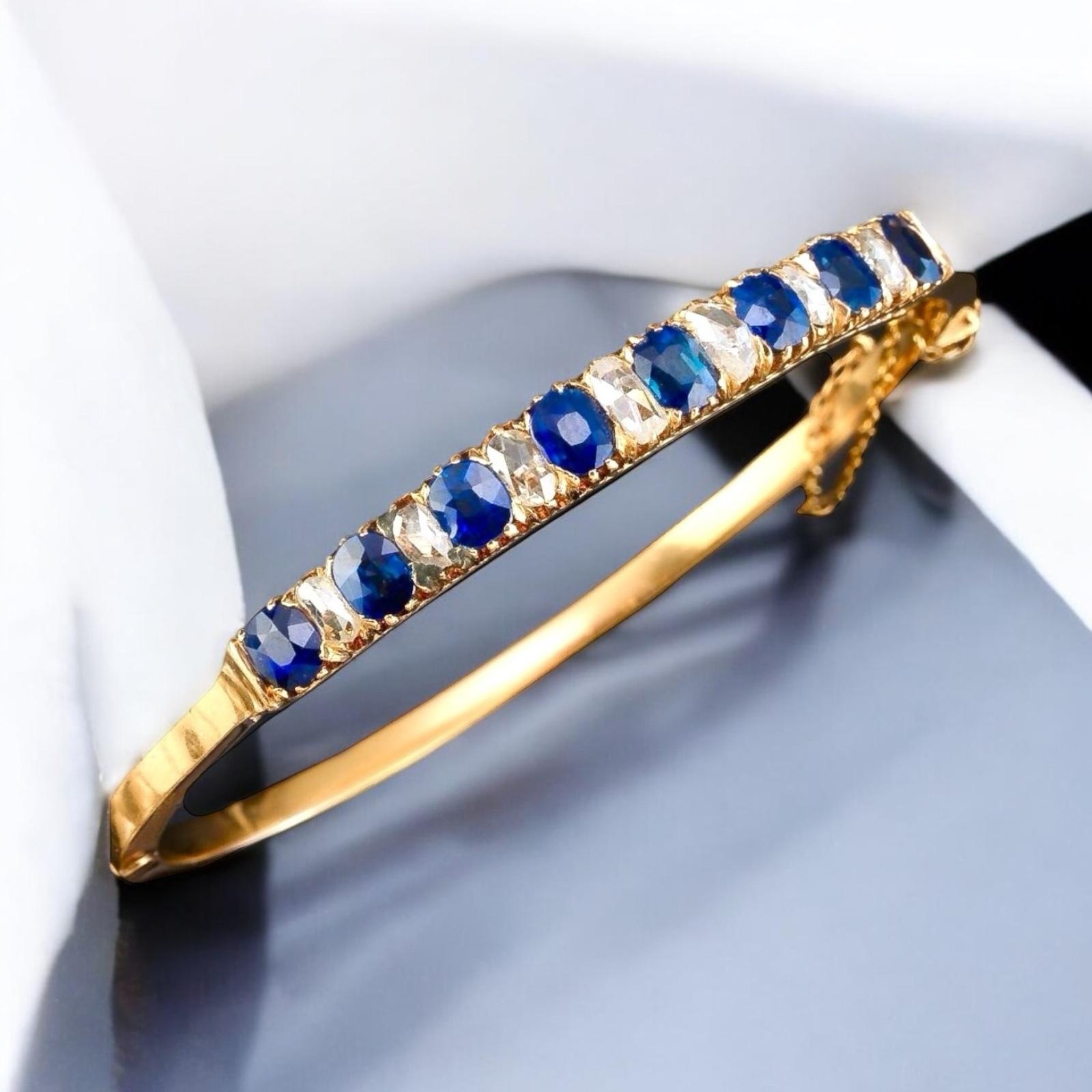 A Victorian sapphire and diamond carved half hoop bangle.
This piece is a Victorian-era sapphire and diamond bangle bracelet, and it’s a stunning example of the fine craftsmanship typical of the mid-to-late 19th century.
A classic hinged bangle