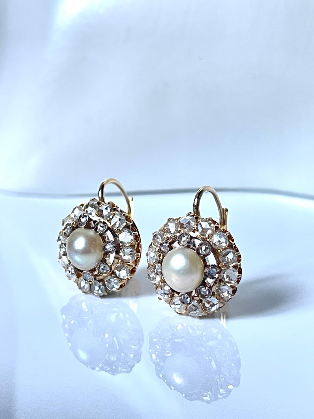 A very delicate pair of late Victorian natural pearl and diamond cluster earrings, each set to the center with a natural saltwater pearl, 7.34 mm in diameter, highlighted by 14 rose cut diamonds in open back claw and grain settings and 8 smaller