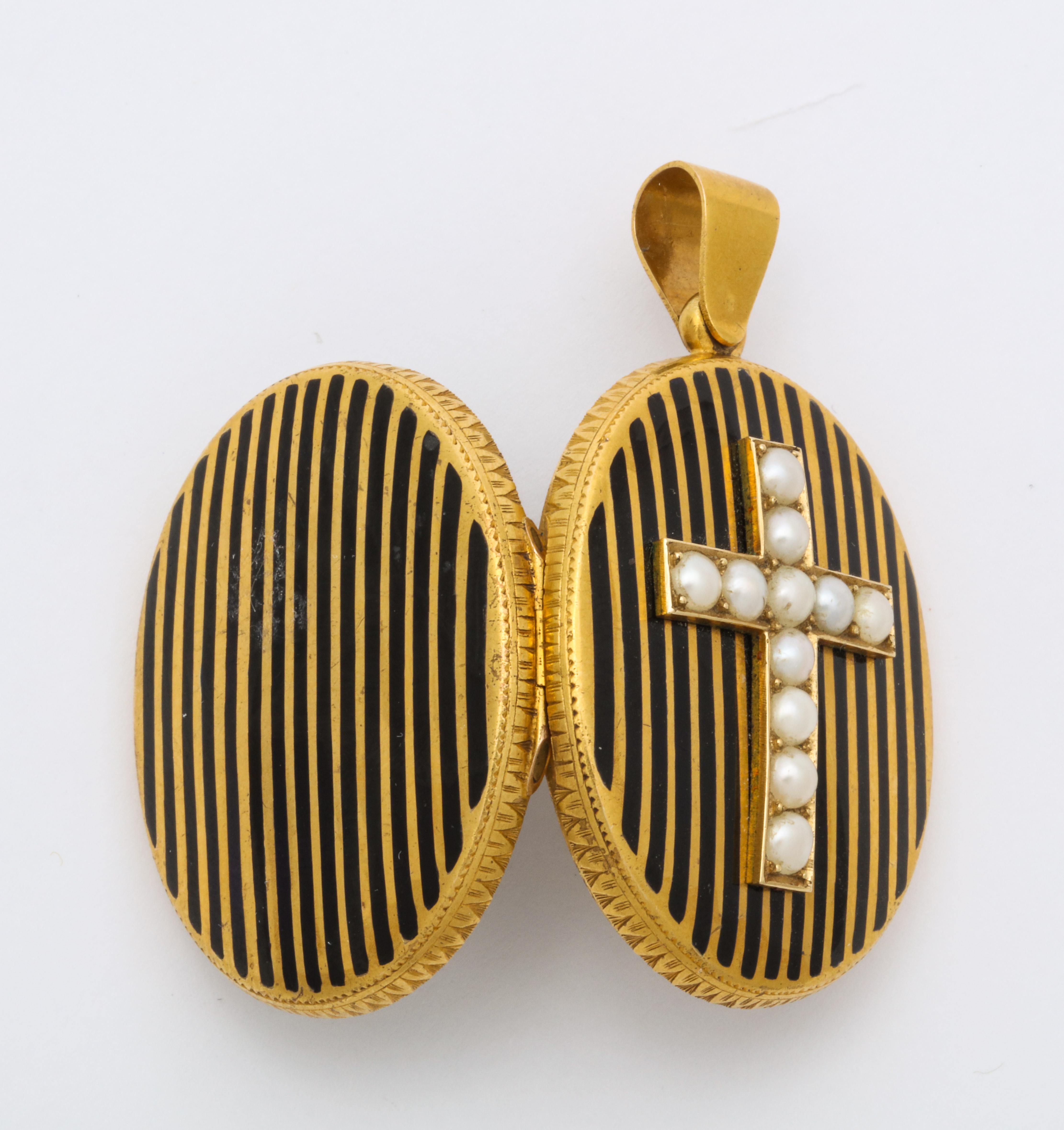 Midpoint on this 18 kt oval locket, set above vertical black enamel stripes, is a cross of radiant natural pearls. The pearls are perfectly matched with no loss to the nacre, the pearlescent layer on the top of the bead. Both front and reverse are