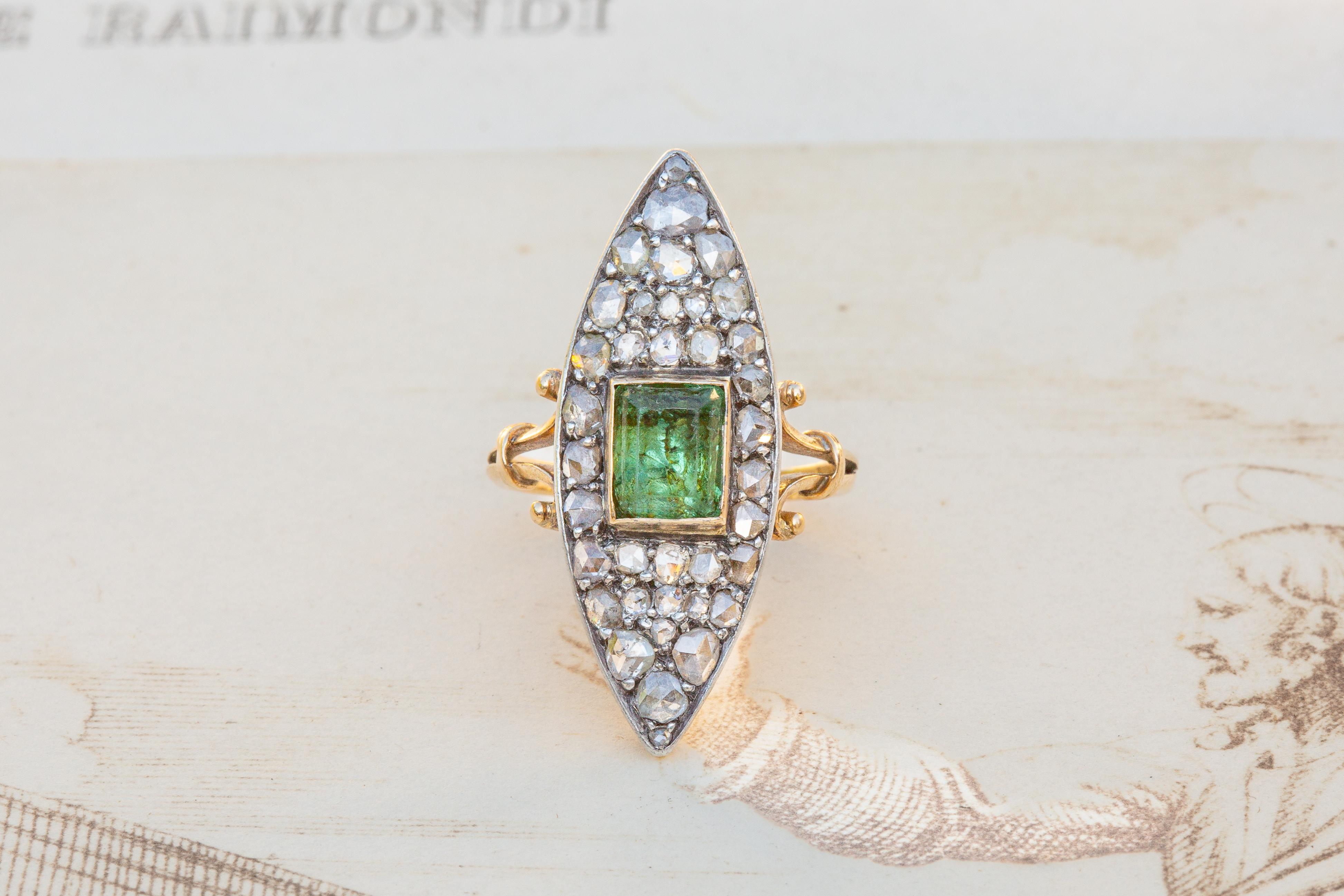 A truly stunning antique Victorian 18K gold ring dating to around 1890. This navette-shaped cluster is constructed with 37 silver set rose cut diamonds surrounding an emerald cut peridot gemstone. The gorgeous pale green peridot is foil-backed and