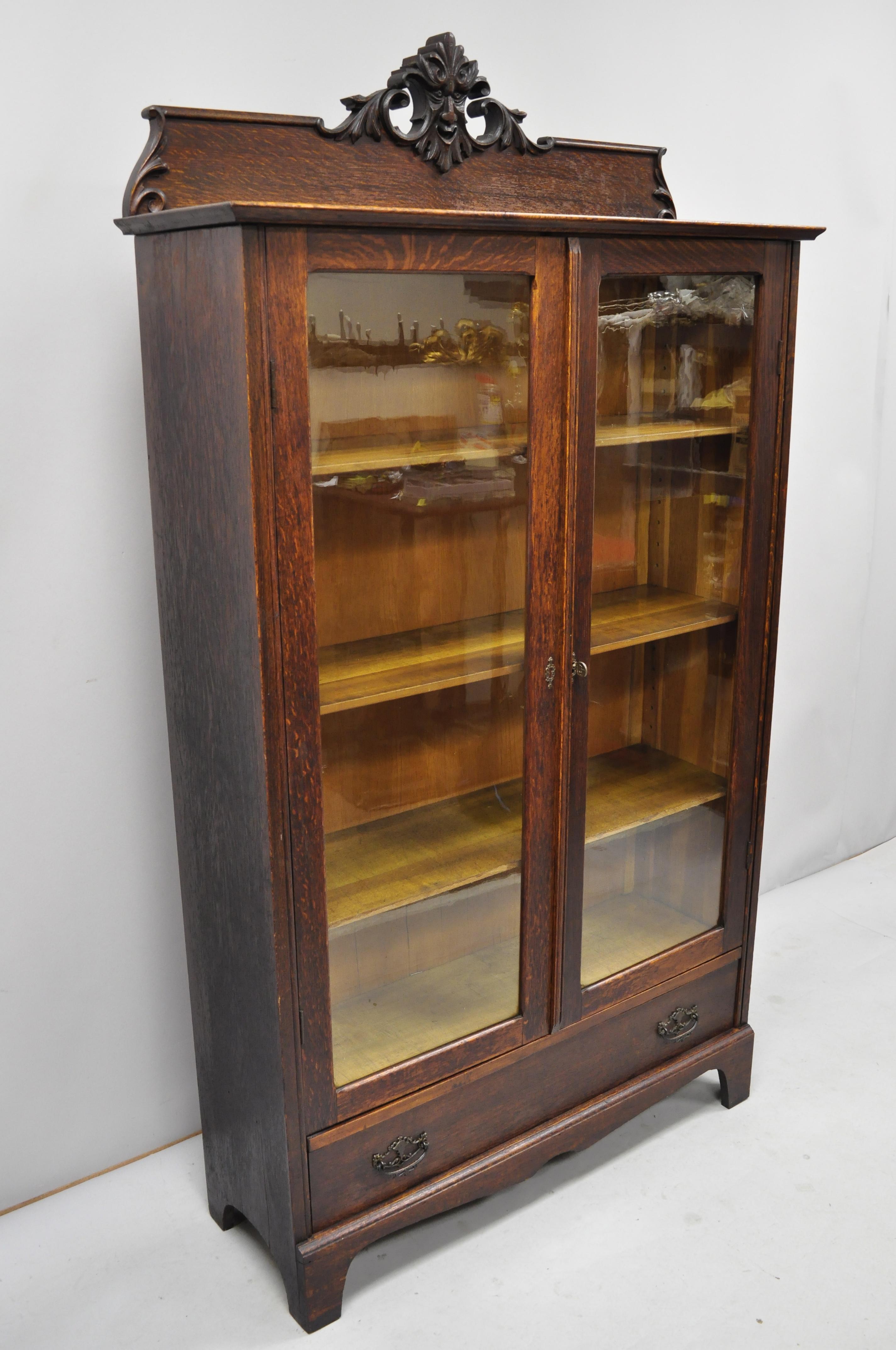 Antique Victorian oak and glass northwind face 2 door bookcase china cabinet.
Item includes carved northwind face, beautiful wood grain, 2 glass swing doors, 1 dovetailed drawer, adjustable shelves, very nice antique item, quality American