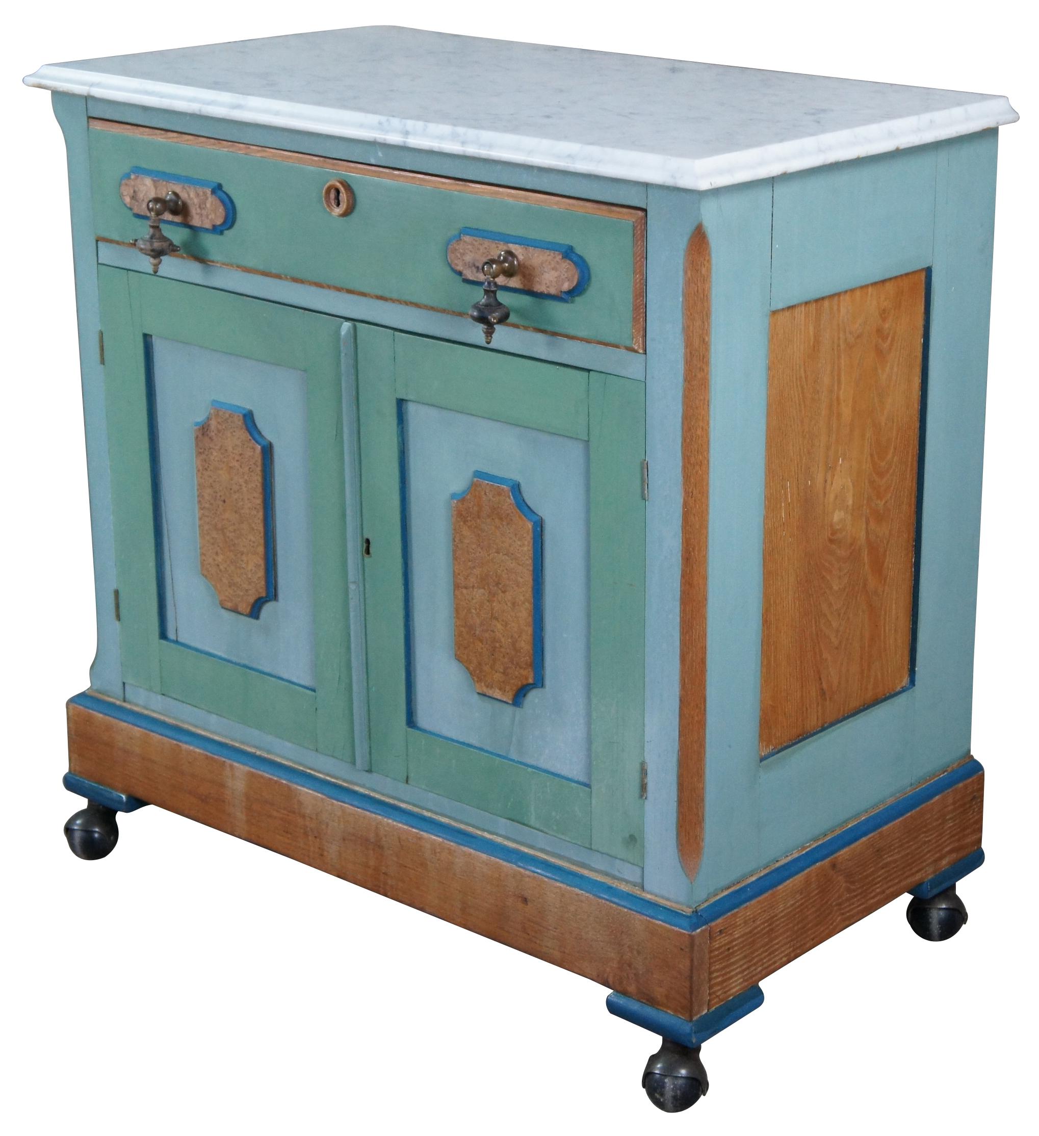 Antique Victorian Eastlake wash stand. Made of oak featuring birdseye maple panels with painted accents, marble top, lower cabinet, and a drawer with brutalist tear drop pulls.
   