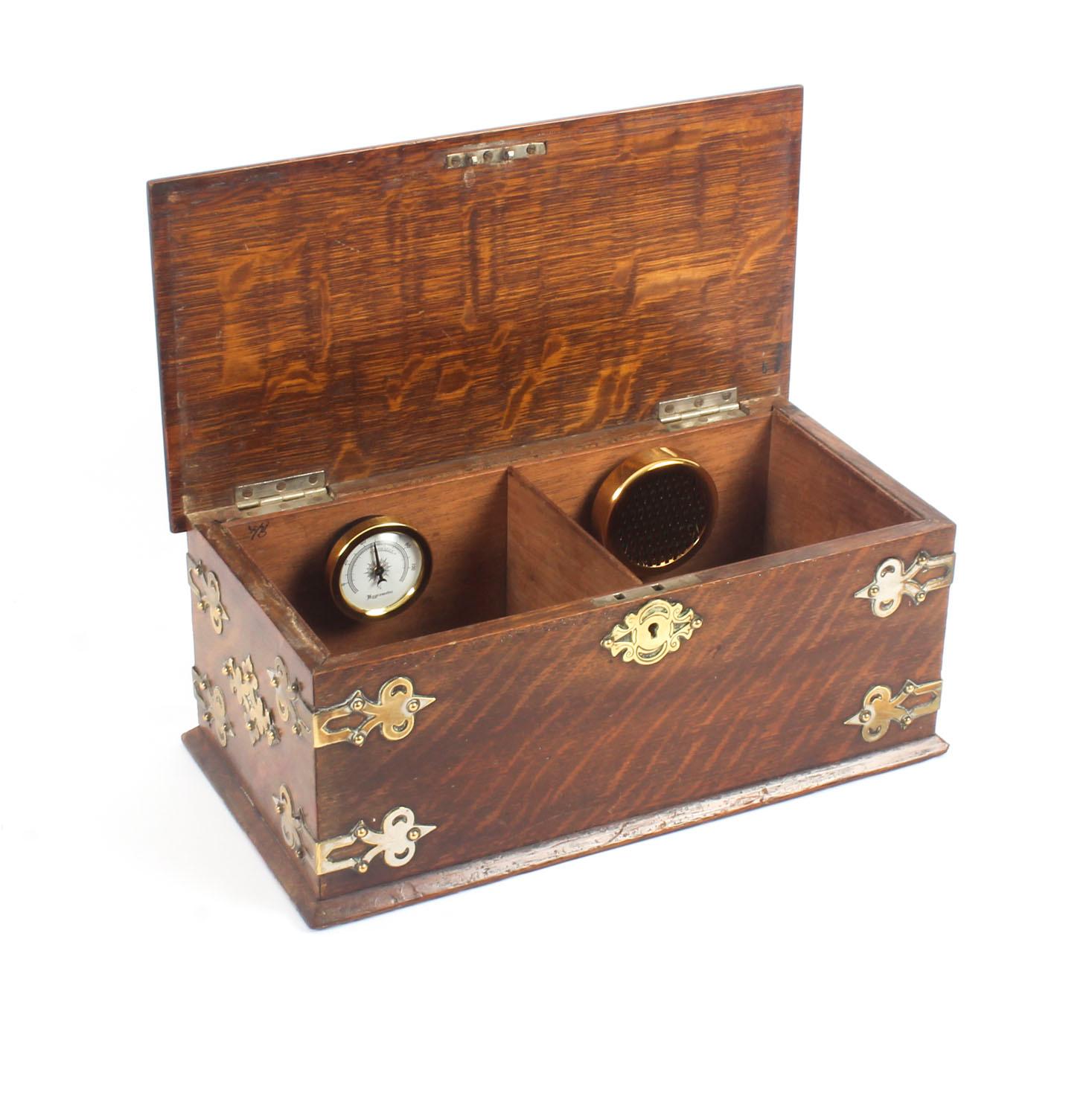 This is a stylish antique Victorian oak and brass-mounted tabletop cigar humidor, circa 1870 in date.

The rectangular box features gothic revival cut card brass mounts with a central handle and an engraved plaque marked 'CIGARS'.

The interior