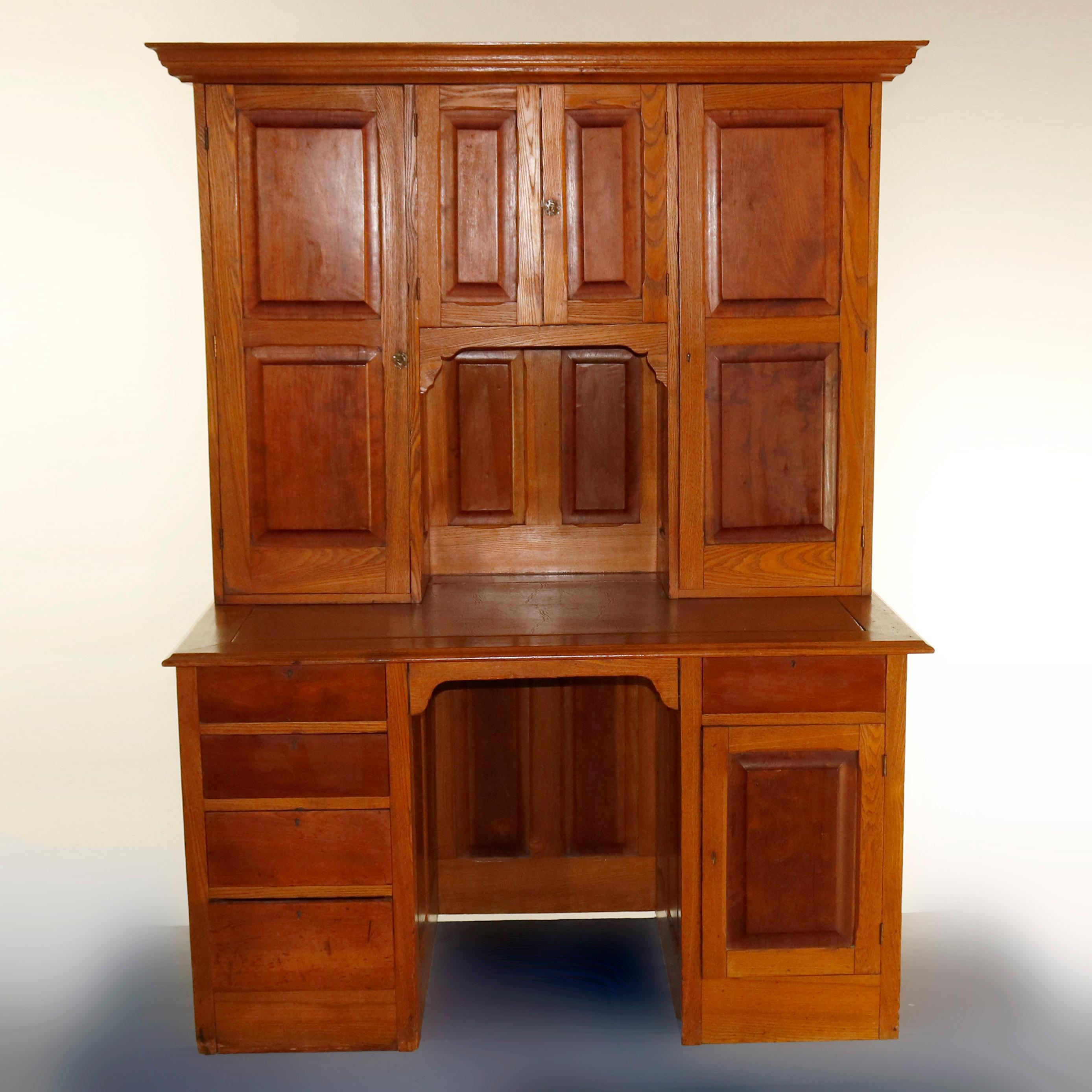 An antique Victorian secretary features oak construction with walnut paneling throughout and has enclosed bookcase surmounting desk with additional drawers and cabinet, c1900

Measures - overall 69