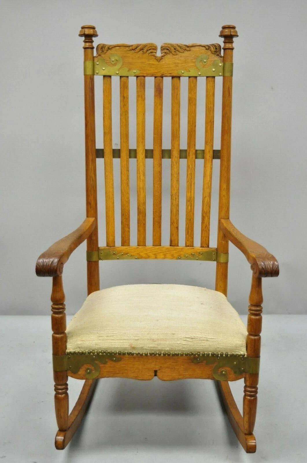 Antique Victorian Oak Wood Arts & Crafts Rocker Rocking Chair with Brass Accents. Item features ornate brass accents, brass rear brace to back, solid wood construction, beautiful wood grain, upholstered seat (with stains), nicely carved details,