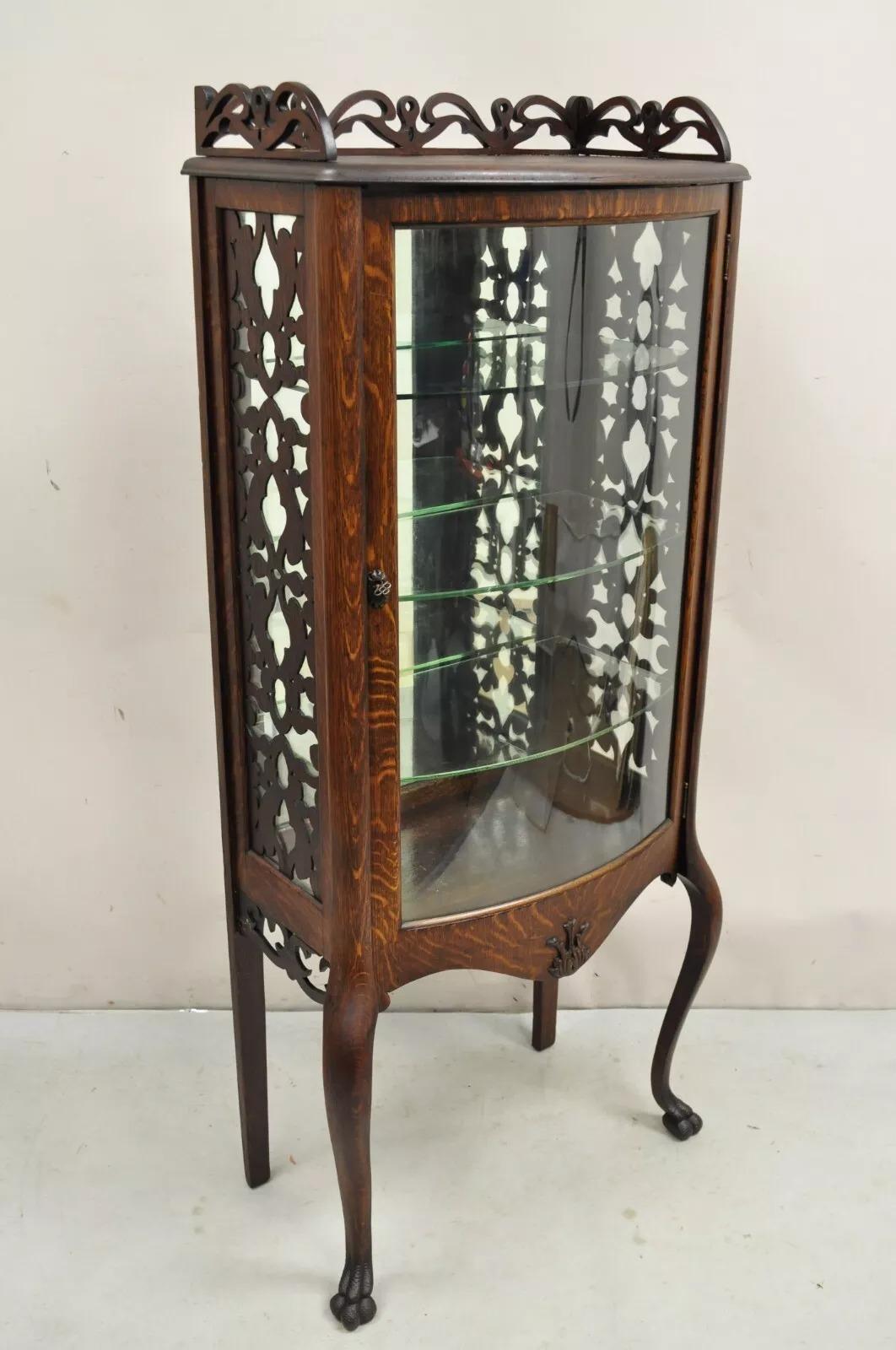Antique Victorian Oak Wood Bowed Glass Single Door Carved Fretwork Curio Cabinet. Item features cabriole legs, paw feet, mirrored back, 3 glass shelves, beautiful wood grain, working lock and key, very nice petite form. Circa Late 19th Century.